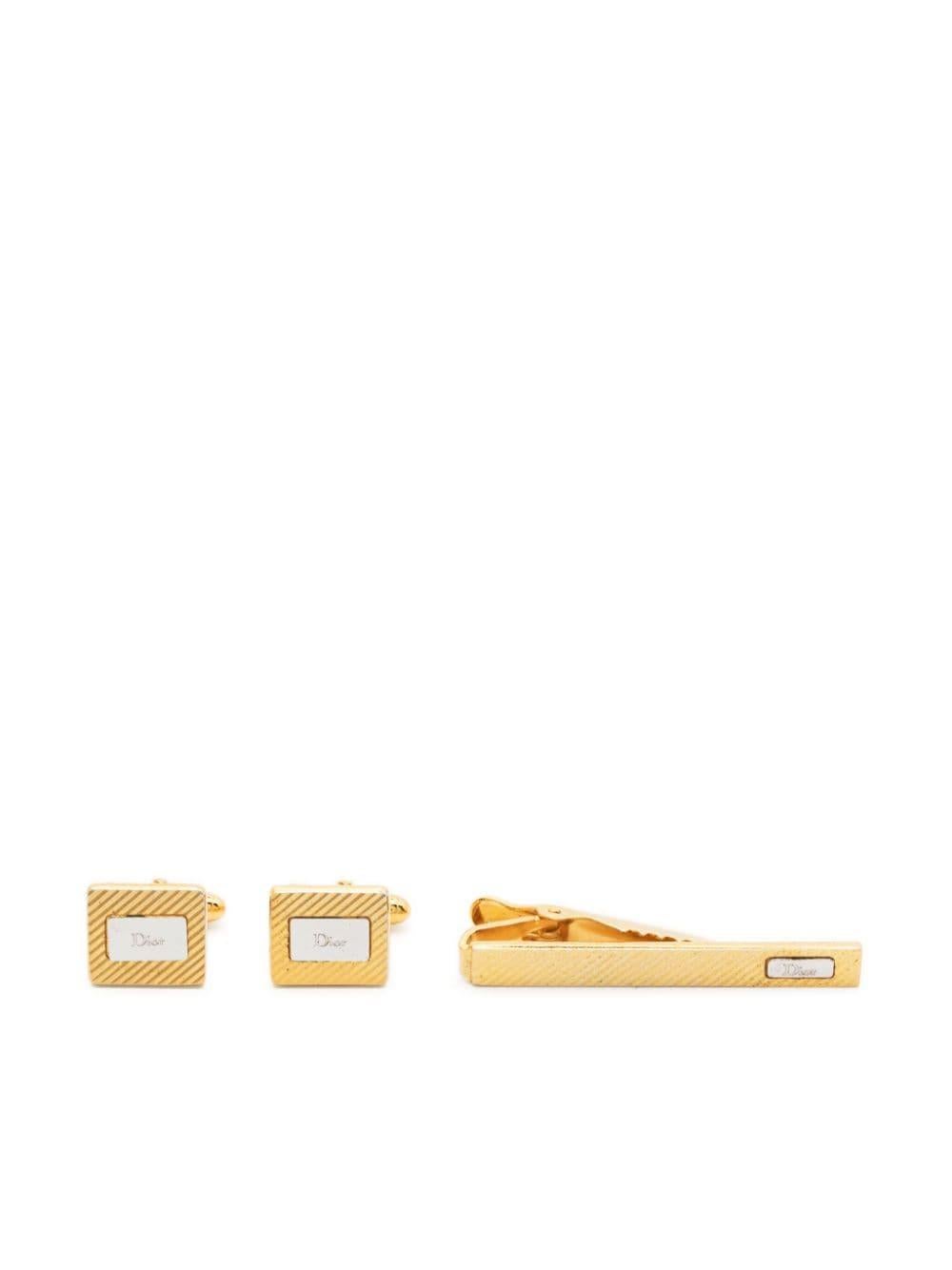 Goldfarbenes Set aus Krawattenklammer und Manschettenknöpfen von Christian Dior mit quadratischem Design mit Logostempel, Drehverschluss und polierter Oberfläche. 
Die  Krawattenspange  mit Clipverschluss, geprägtem Logo auf der Vorderseite und