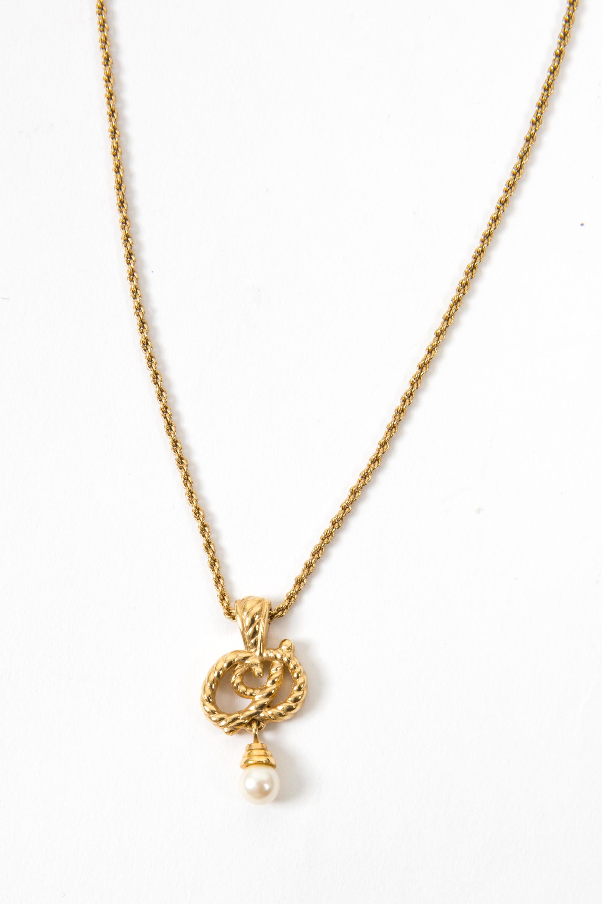 Collana a catena Christian Dior in tonalità oro con catena sottile, medaglia centrale con firma CD impreziosita da una finta perla e chiusura con logo. 
In buone condizioni vintage. Prodotto in Francia.
Circa: anni '90
Lunghezza: 45 cm (17,7