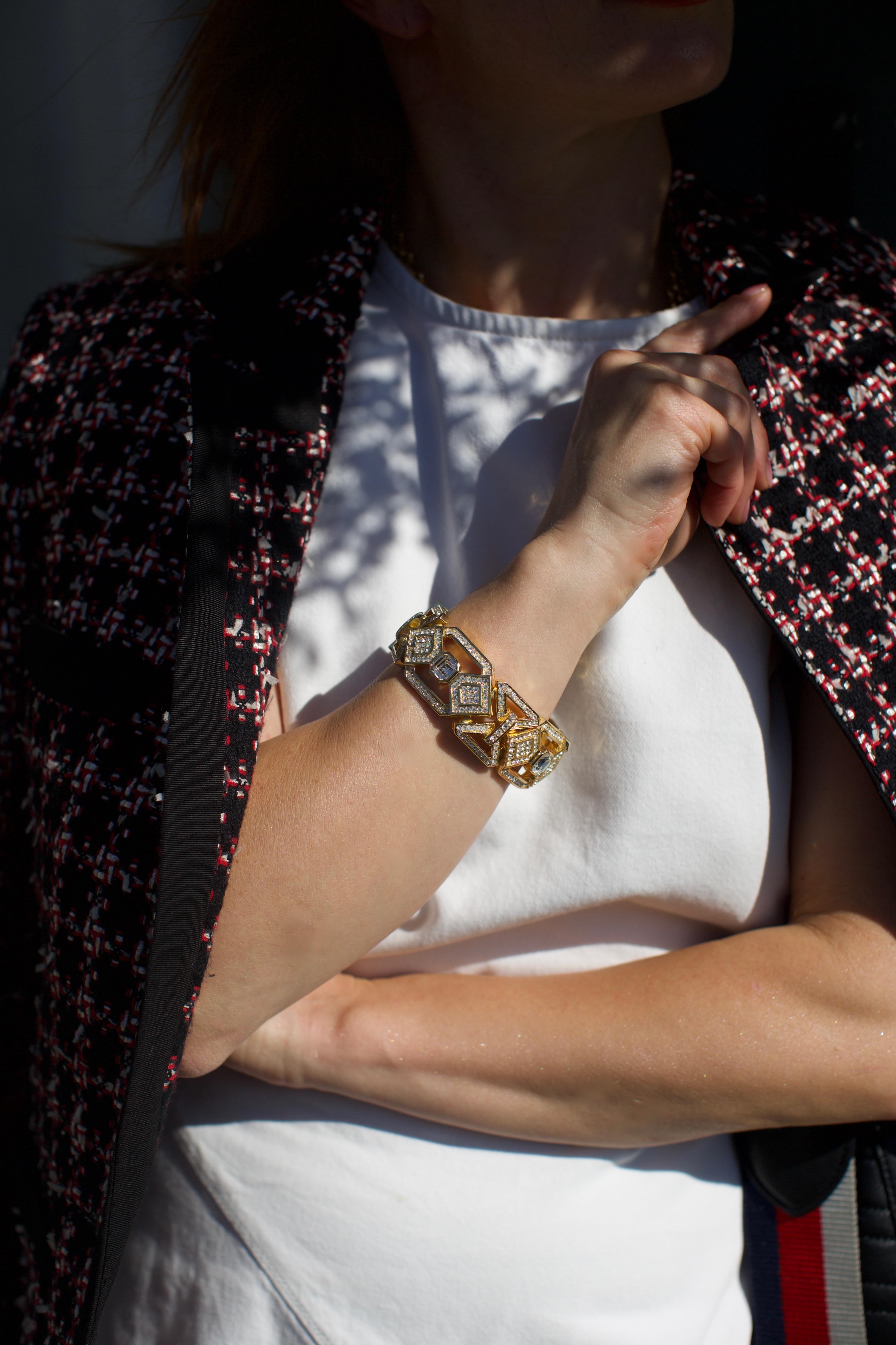 A striking vintage Christian Dior bracelet from the 1980s, crafted in a bold geometric link design. The bracelet is gold-toned and pavé-set with clear rhinestones, with larger central stones accentuating the repeating diamond-shaped motifs. Retains