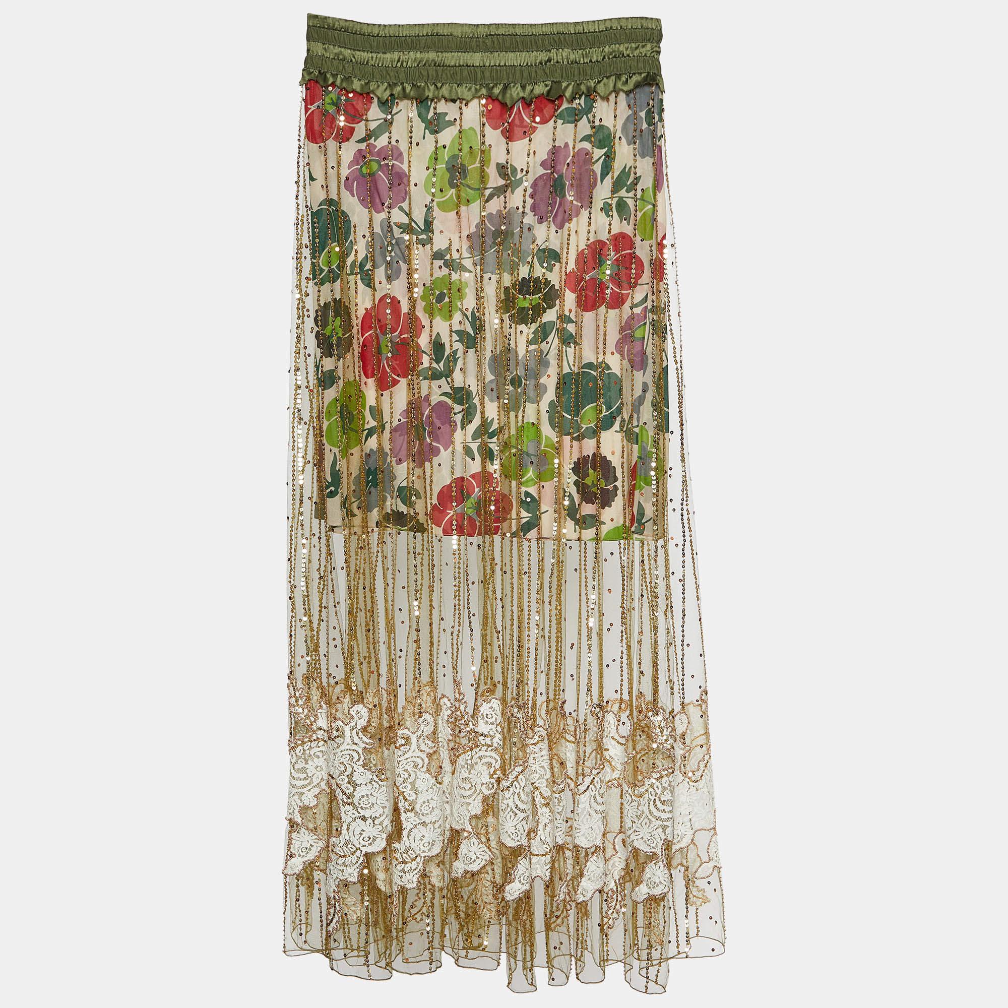 The Christian Dior skirt is a breathtaking piece of fashion artistry. Featuring a luxurious gold tulle overlay adorned with vibrant floral prints, this skirt is elegantly lined with silk, creating a stunning and romantic look for any special