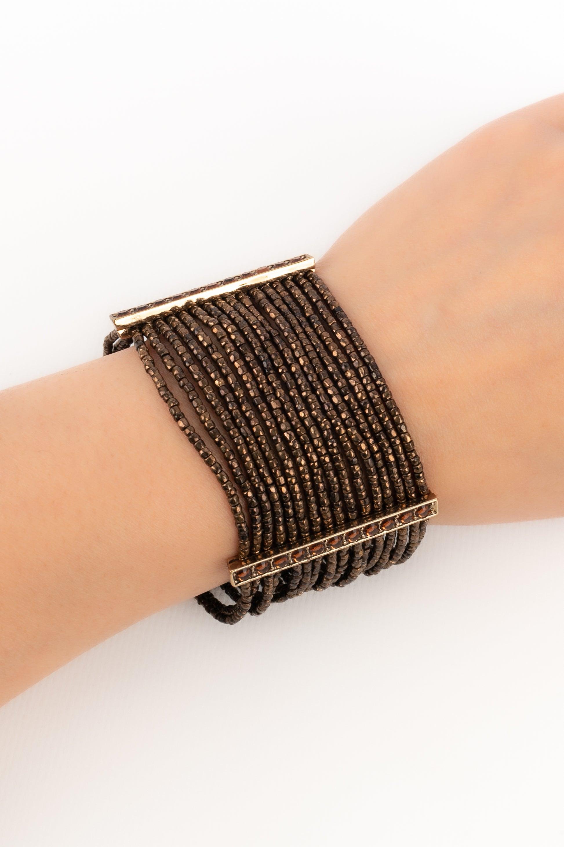 Dior - Golden metal bracelet ornamented with orange rhinestones and rows of coppery pearls.

Additional information:
Condition: Very good condition
Dimensions: Length: 19 cm

Seller Reference: BRA120