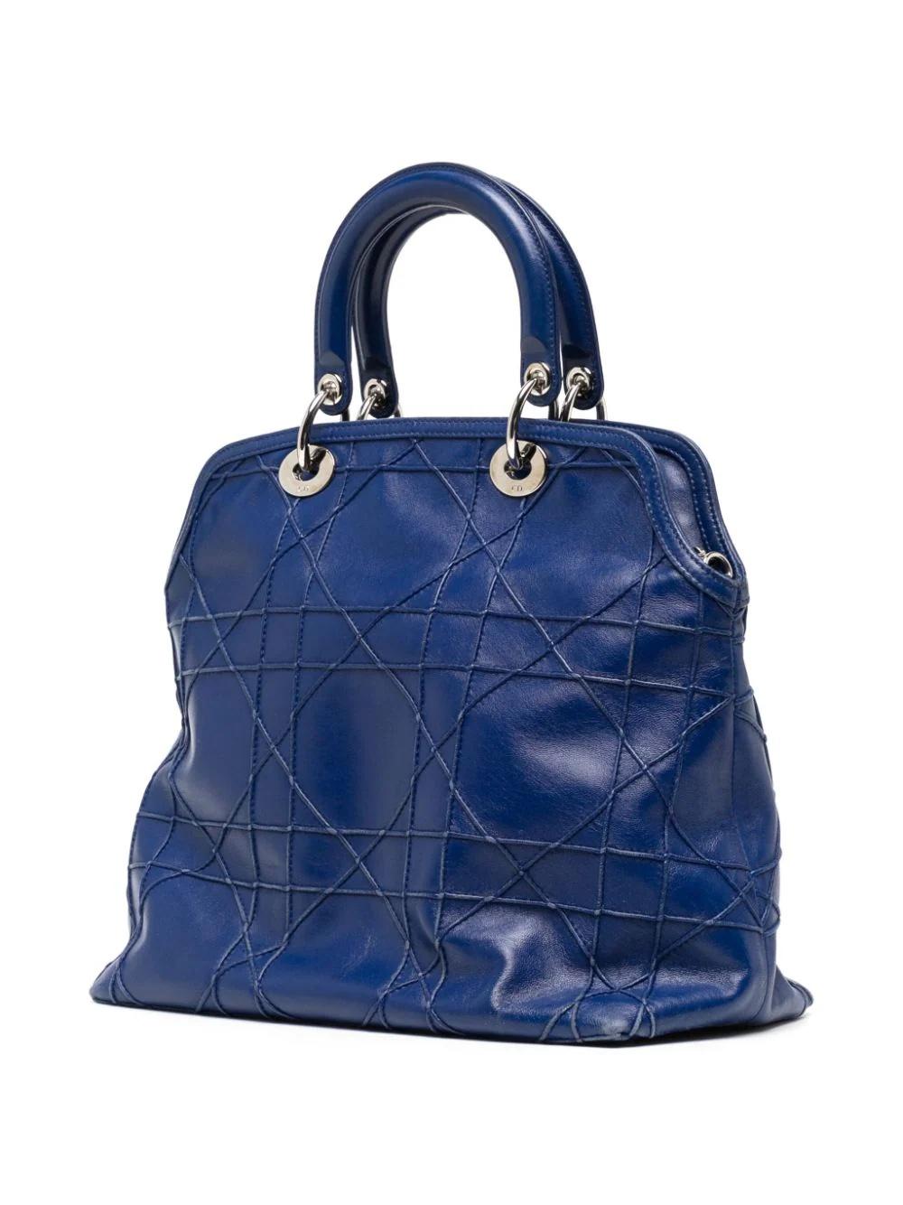 The navy-blue leather Granville tote from Christian Dior features the Cannage quilt design inspired by Napoléon II Cannage chairs. It is finished with the hallmark Dior letters charm in silver-tone hardware, adding a unique and charming