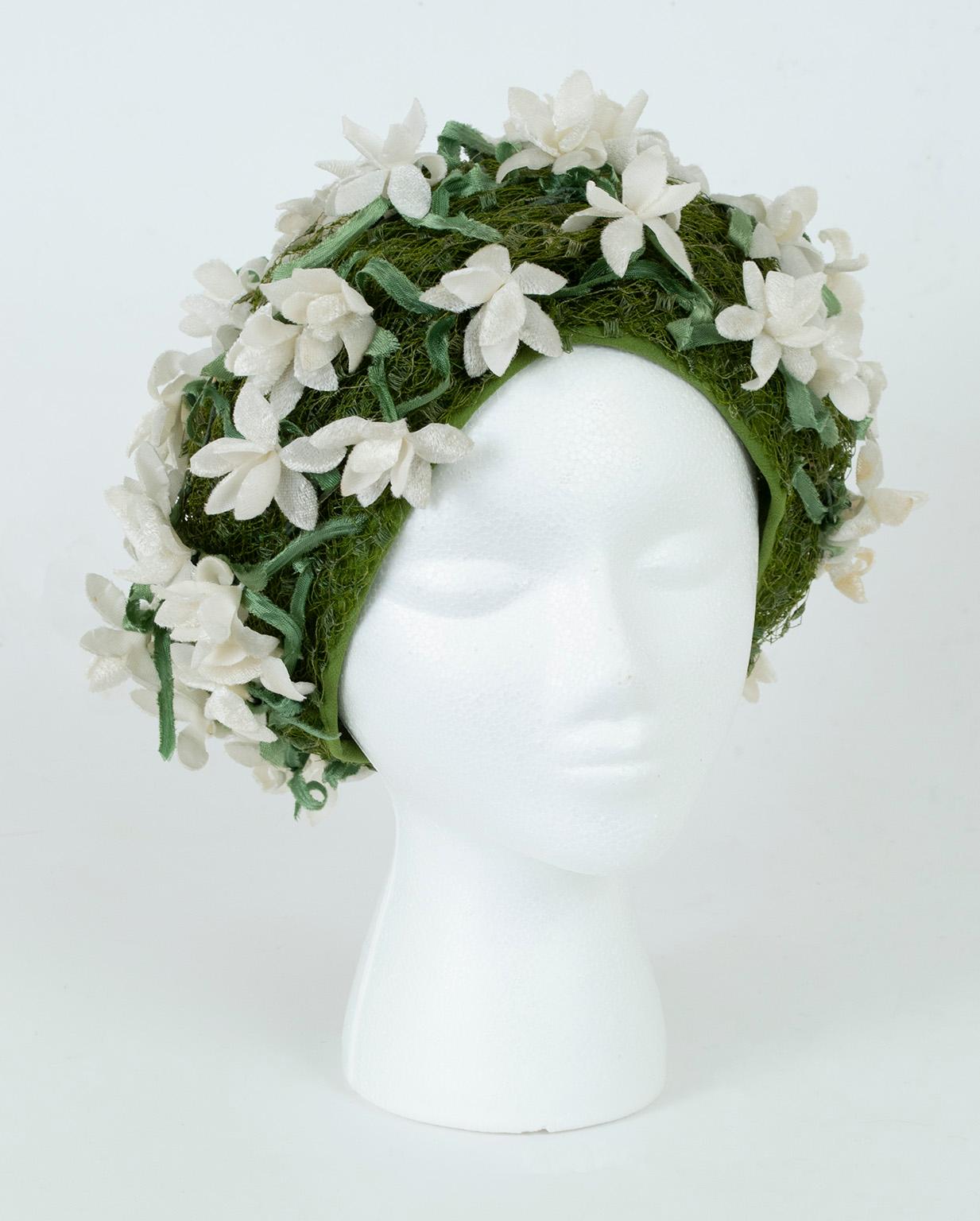 A dream accessory, this unbelievable Dior hat uses green silk and veiling to simulate a ground of grass, while articulated silk velvet gardenias and leaves cover its surface. Replete with texture and dimension, its dramatic silhouette, color and