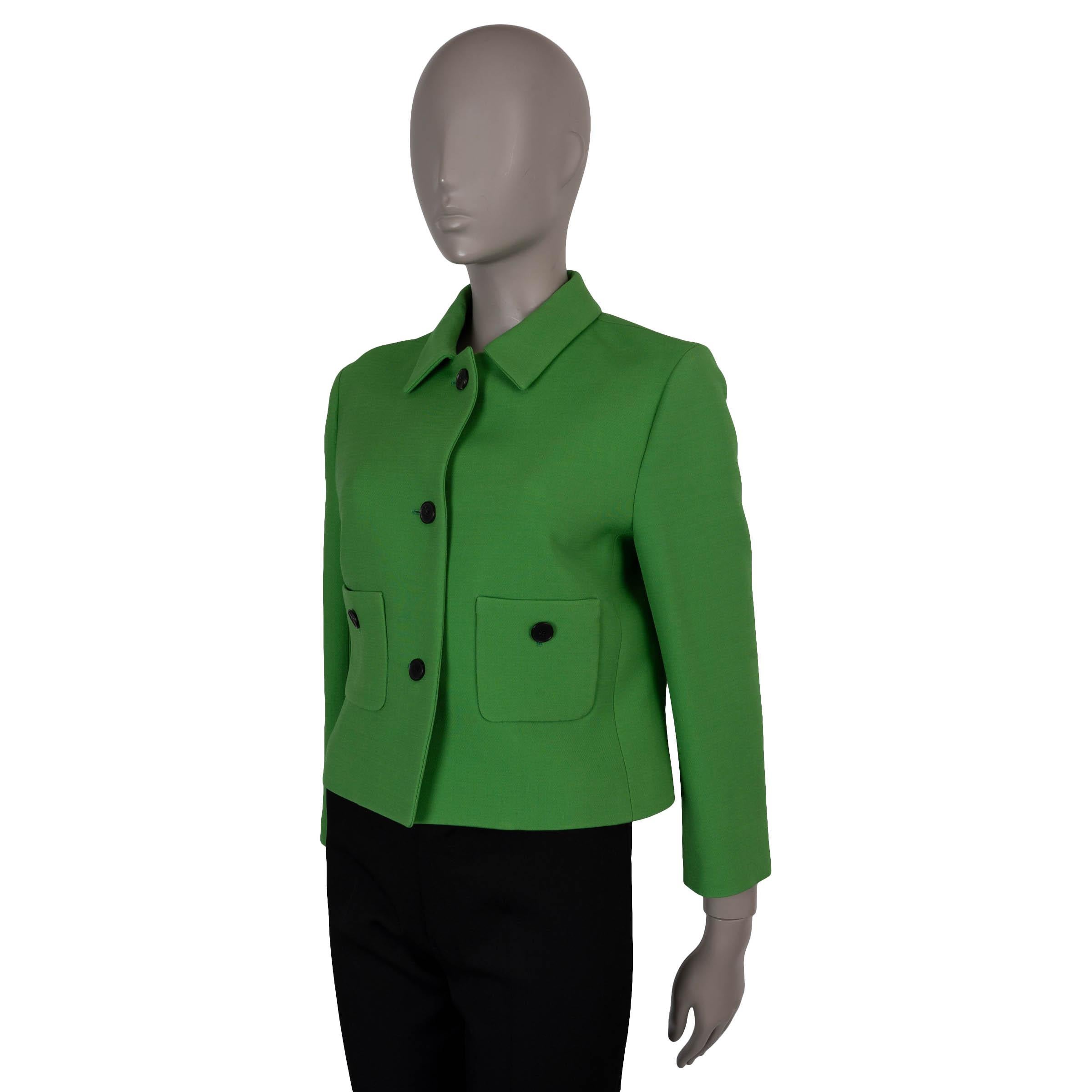 Questa giacca 100% autentica di Christian Dior è realizzata in lana (77%) e seta (23%) di colore verde erba e mette in mostra la raffinata sartoria della Maison. Con una silhouette squadrata e una lunghezza ridotta, presenta un colletto a punta, due