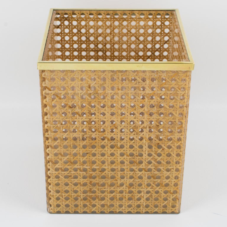 Lovely wastebasket or planter designed for Christian Dior Home Collection in the 1970s. Geometric shape with brass gallery and real rattan cane work embedded in the crystal clear Lucite. Great desk or home accessory for any modern