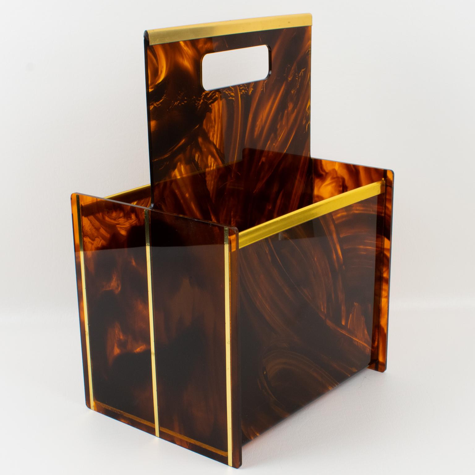 Stylish 1970s magazine rack, holder, or stand designed for the Christian Dior Home Collection in the 1970s. Geometric shape with polished brass trim gallery and accents and faux tortoiseshell (tortoise) textured pattern Lucite. Great accessory for