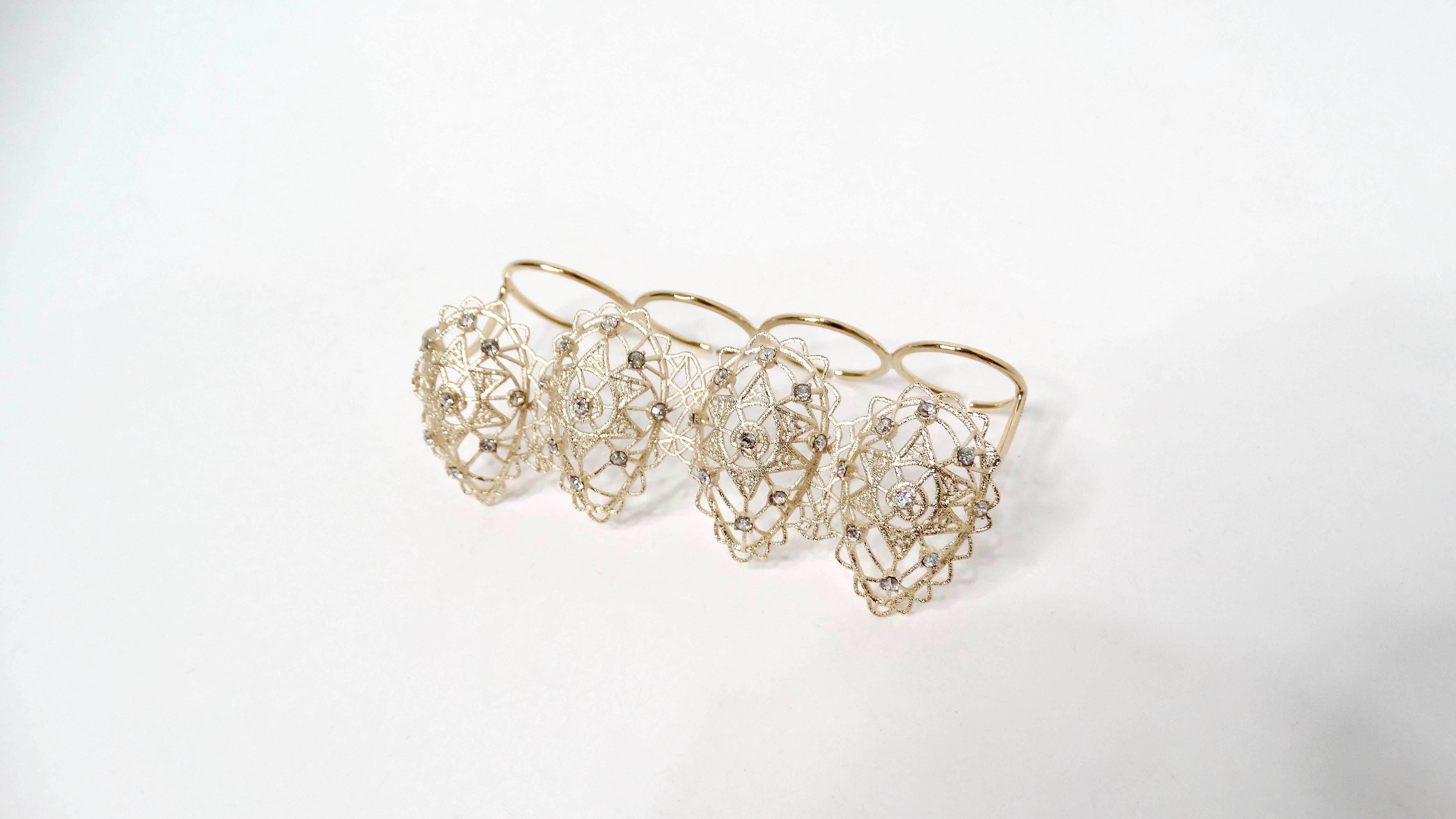 The Christian Dior Intricate Crystal Detailed Gold-Tone Four-Finger Statement Ring is a bold piece of costume jewelry designed to make a statement. Crafted with a gold-tone finish, this ring features a four-finger wire design, offering a unique and