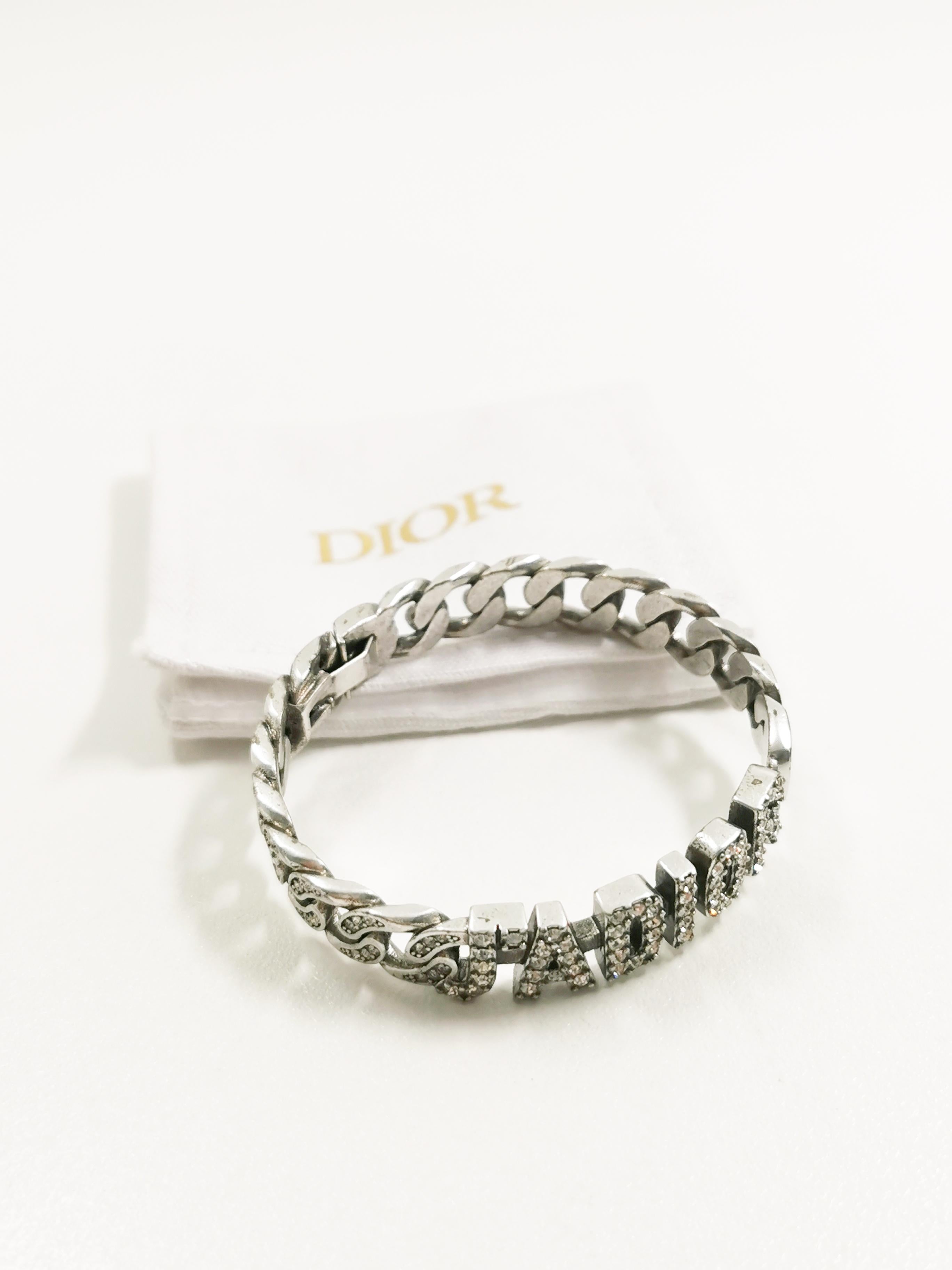 The Christian Dior J'adior Alphabet Rhinestones Cuff Silver Bangle Bracelet is an exquisite and luxurious piece of jewelry that seamlessly combines the iconic Dior style with a touch of personalization. This bangle bracelet is a part of the renowned