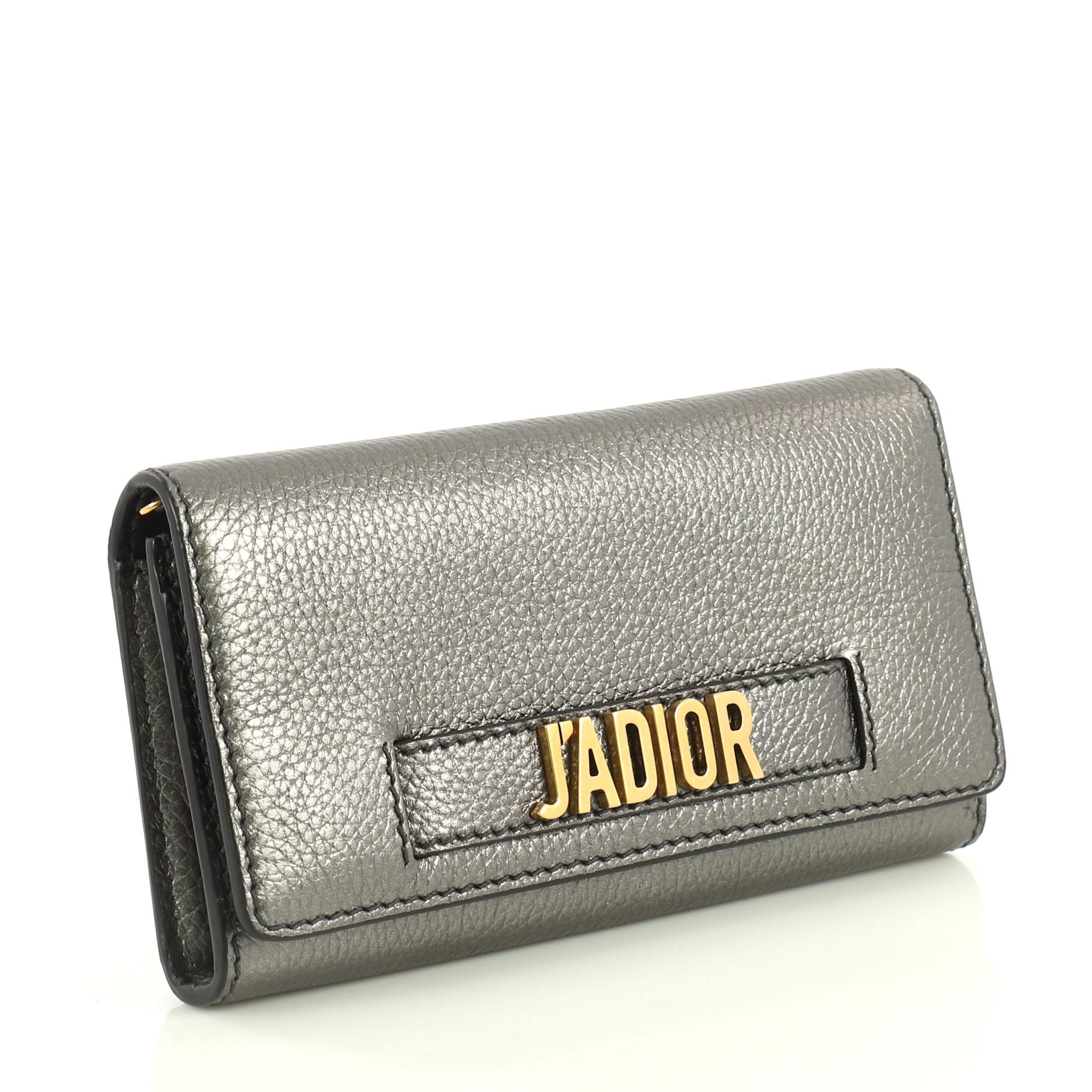 This Christian Dior J'adior Croisiere Chain Wallet Leather, crafted from gray metallic leather, features chain link strap, slot handclasp with metal plated J'adior signature, and aged gold-tone hardware. Its flap opens to a gray nylon interior with