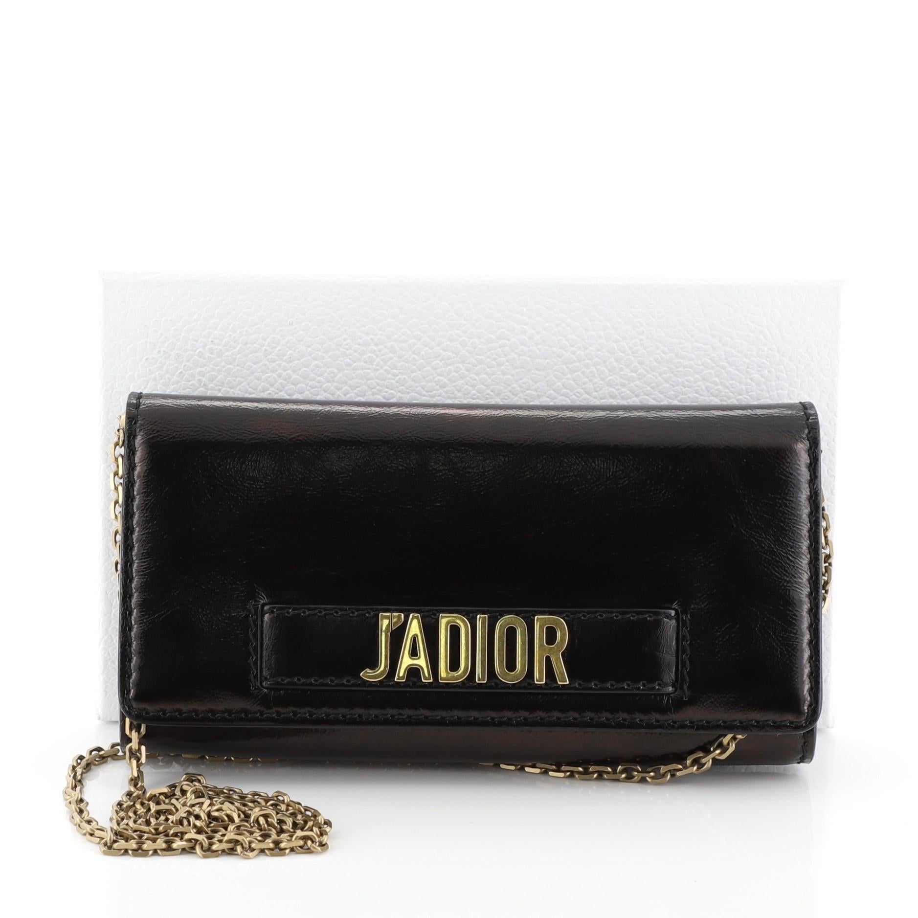 This Christian Dior J'adior Croisiere Chain Wallet Leather, crafted from black leather, features chain link strap, slot handclasp with metal plated J'adior signature, and aged gold-tone hardware. Its flap opens to a black leather interior with