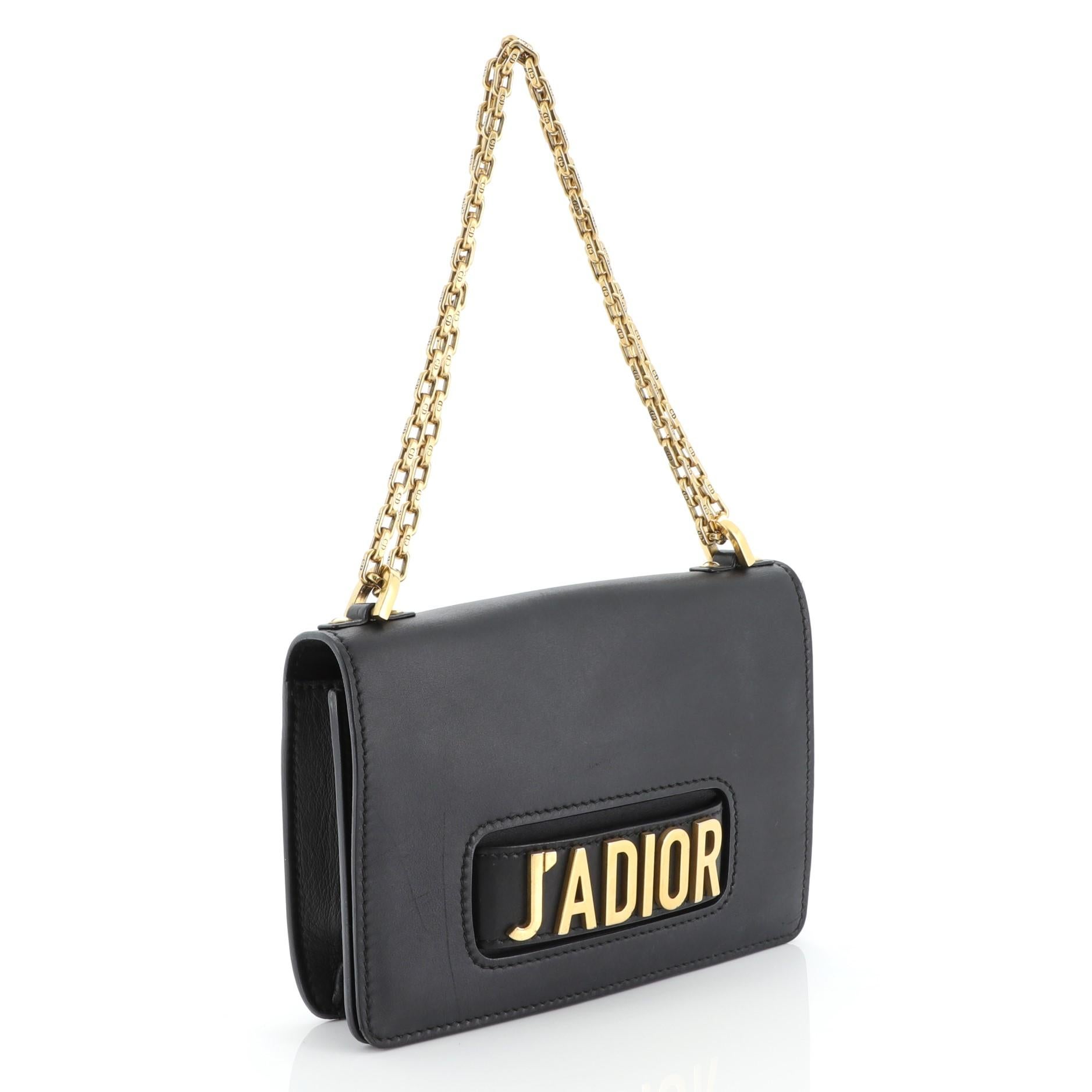This Christian Dior J'adior Flap Bag Calfskin Medium, crafted in black leather, features a slot handclasp with metal plated J'ADIOR signature, chain link strap, full front flap and gold-tone hardware. It opens to a black suede interior with flap and