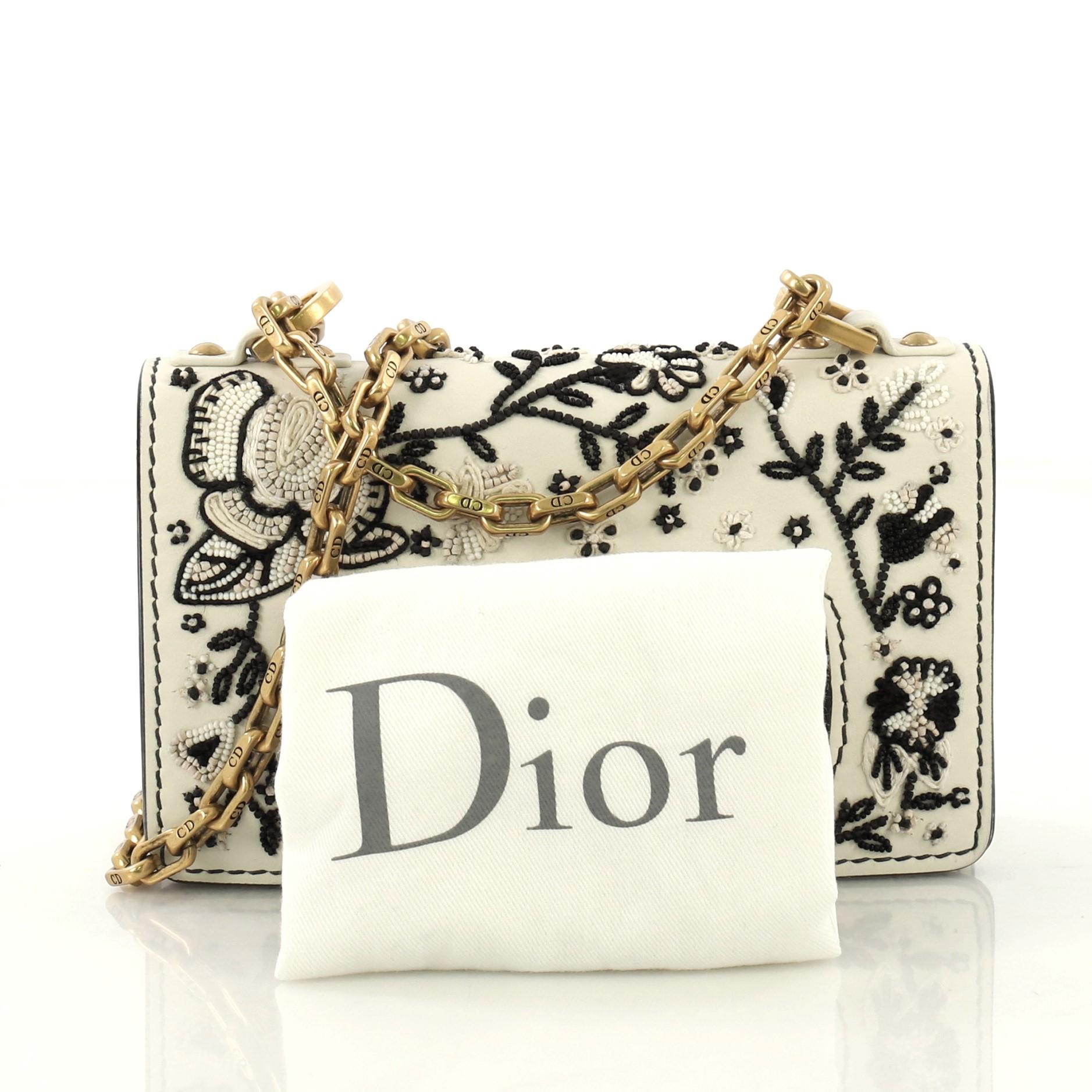 This Christian Dior J'adior Flap Bag Embellished Leather Mini, crafted from white embellished leather, features chain link strap, slot handclasp with metal plated J'adior signature, and aged gold-tone hardware. Its flap opens to a white suede