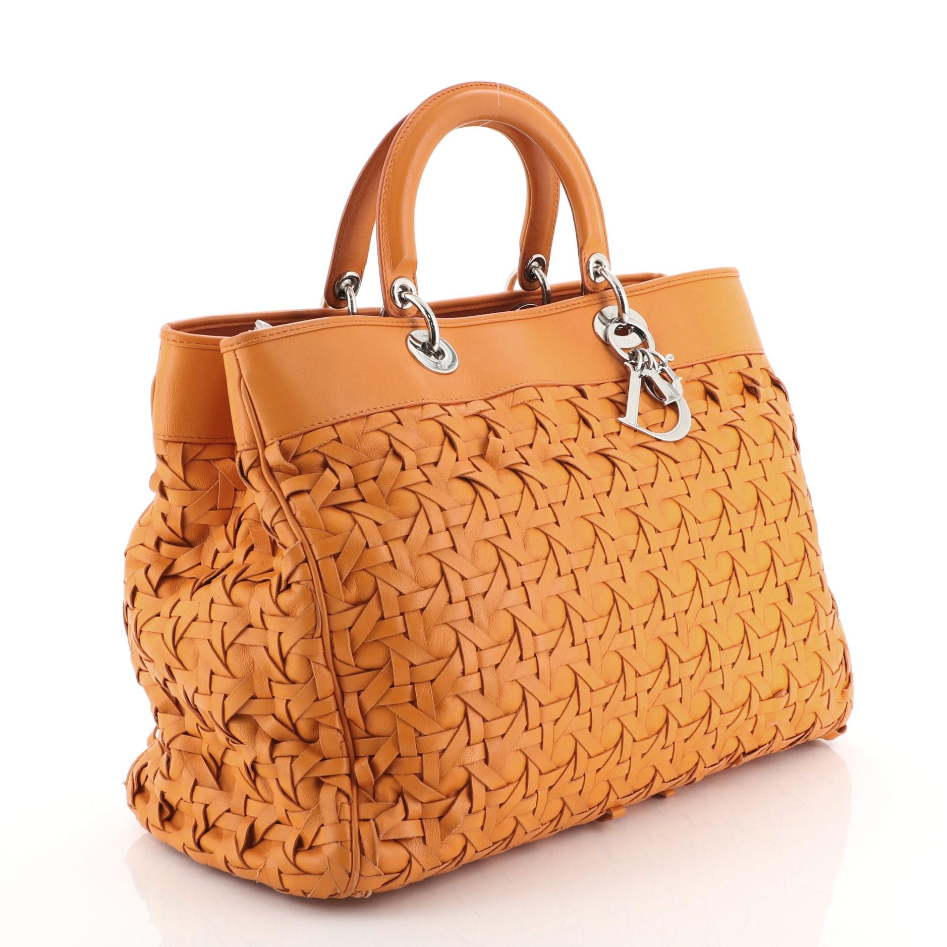 This Christian Dior Lady Dior Avenue Bag Woven Leather Large, crafted from orange woven leather, features dual leather top handles, protective base studs, and silver-tone hardware. It opens to an orange leather interior divided into two open