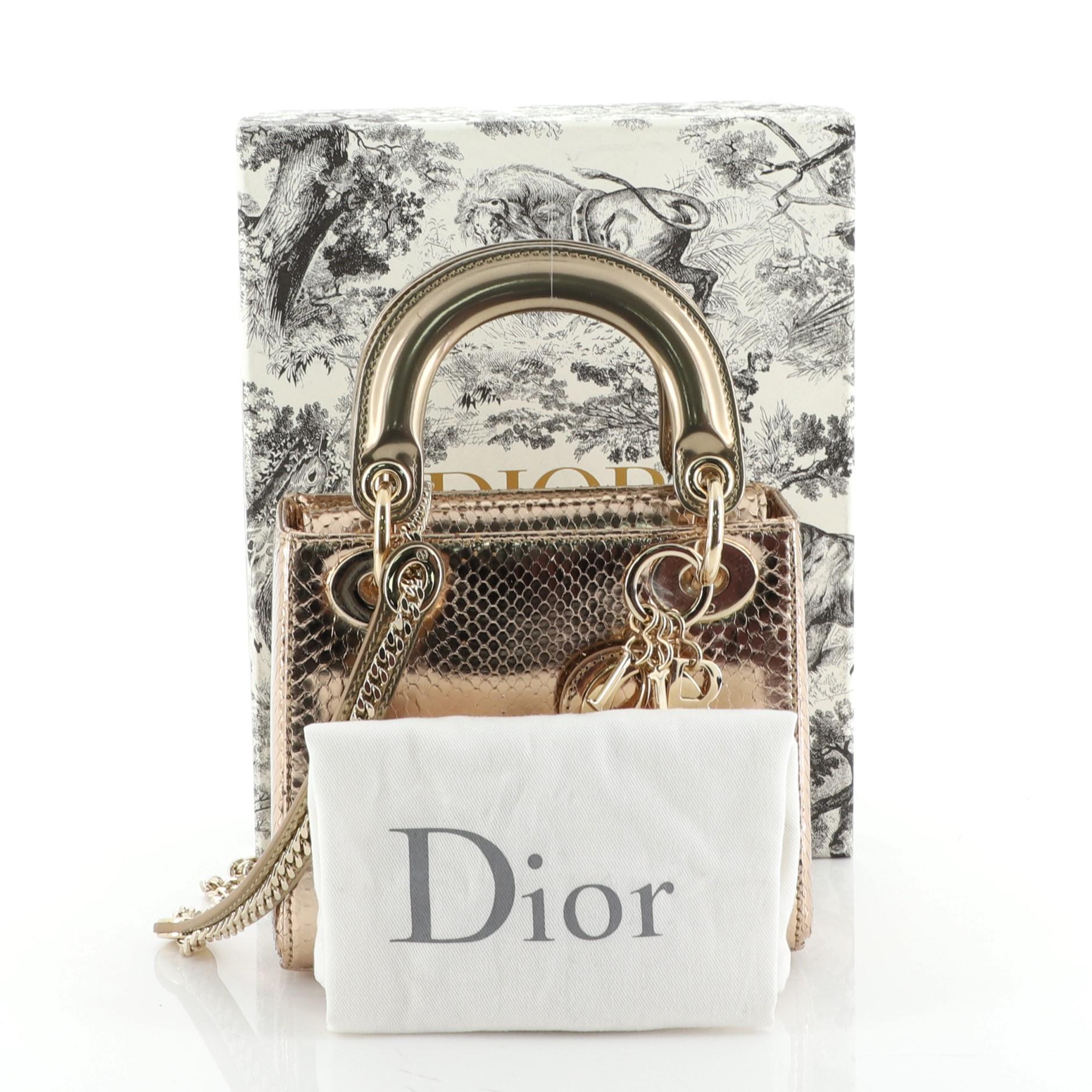 This Christian Dior Lady Dior Bag Python Mini, crafted in genuine gold python, features dual top leather handles, Dior charms, and gold-tone hardware. It opens to a pink leather interior with side zip pocket. This item can only be shipped within the