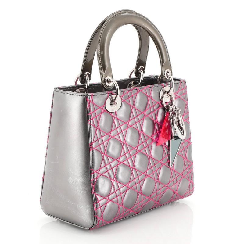 This Christian Dior Lady Dior Handbag Anselm Reyle Cannage Quilt Leather Medium, crafted from multicolor silver cannage quilt leather, features smooth short dual handles with colorful triangular Dior charms, and silver tone hardware. Its zip lock