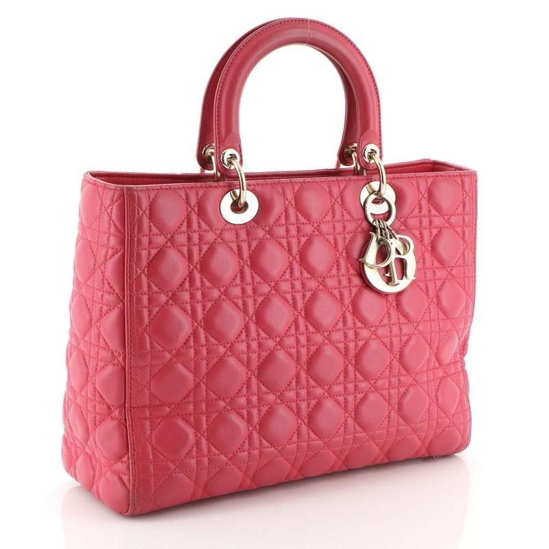 This Christian Dior Lady Dior Handbag Cannage Quilt Lambskin Large, crafted in pink cannage quilted lambskin leather, features dual short handles with Dior charms and gold-tone hardware. Its zip closure opens to a gray fabric interior with zip