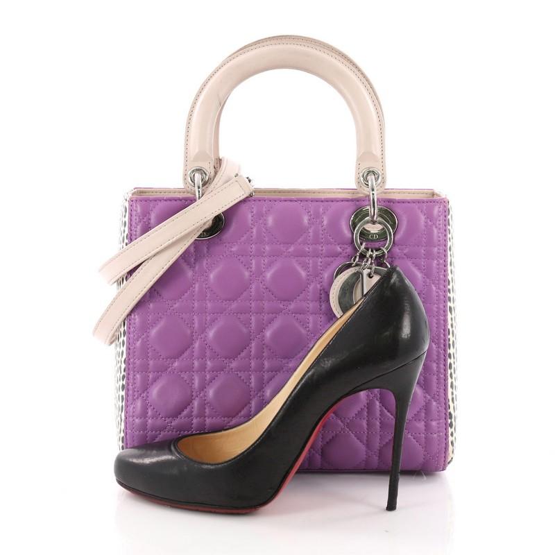 This Christian Dior Lady Dior Handbag Cannage Quilt Lambskin with Python Medium, crafted in purple lambskin leather with genuine python skin, features cannage quilting, dual rolled handles, and silver-tone hardware. Its top zip closure opens to a