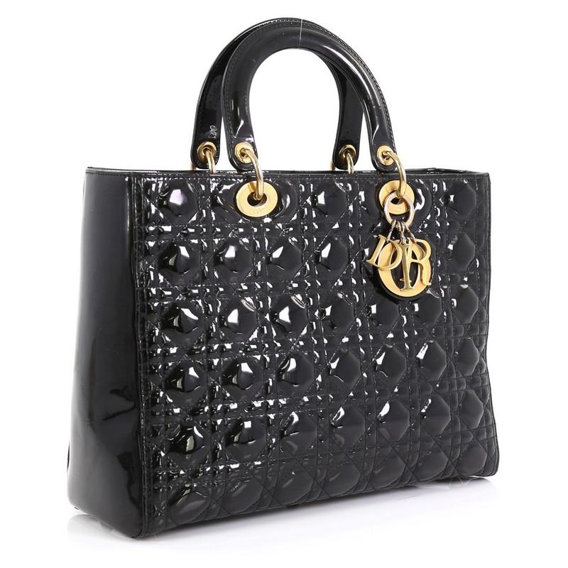 This Christian Dior Lady Dior Handbag Cannage Quilt Patent Large, crafted in black cannage quilt patent leather, features dual top leather handles, Dior charms, and gold-tone hardware. Its zip closure opens to a black fabric interior with side zip