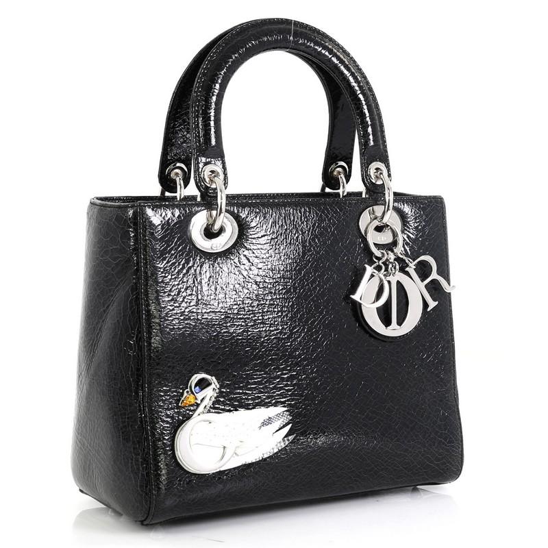 This Christian Dior Lady Dior Handbag Limited Edition Embellished Crackled Deerskin Medium, crafted from black embellished crackled deerskin, features short dual handles with Dior charms, protective base studs and silver-tone hardware. It opens to a