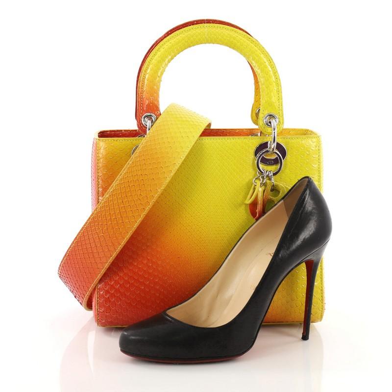 This Christian Dior Lady Dior Handbag Python Medium, crafted in genuine orange and yellow python skin, features dual rolled handles with sleek Dior charms, and silver-tone hardware. Its top zipper closure opens to an orange leather interior with