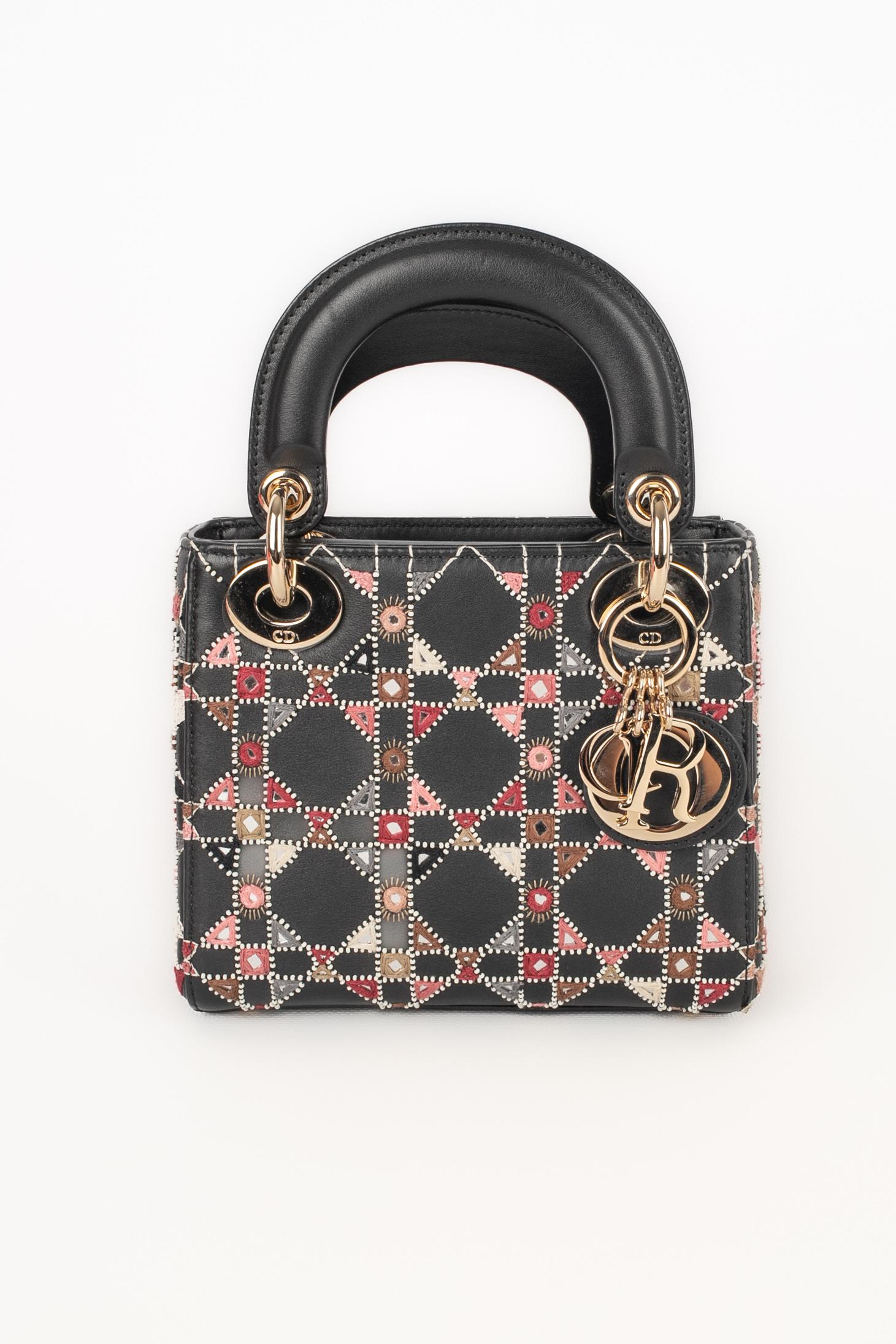DIOR - (Made in Italy) Black calfskin Lady Dior mini bag embroidered with caneworked pearls, mirrors, Dior charms, and a removable thin chain strap. Piece with an authenticity card. A 2019 Collection.

Condition:
Very good