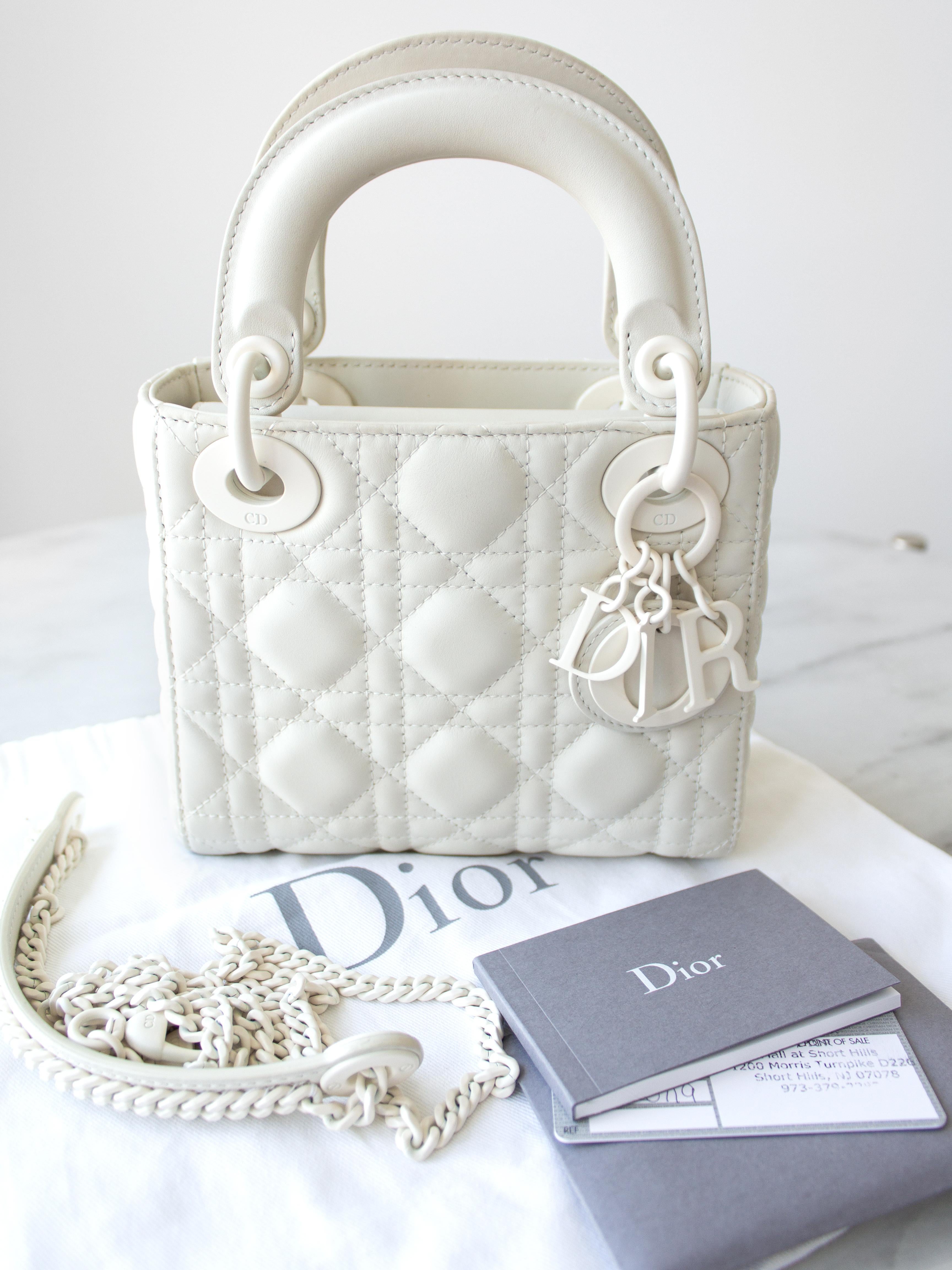 The ultra matte Lady Dior bag in mini size is a highly sought-after piece from 2019. Crafted in elegant matte white calfskin leather with a tonal suede lining, this bag exudes sophistication. It features leather top handles adorned with the classic