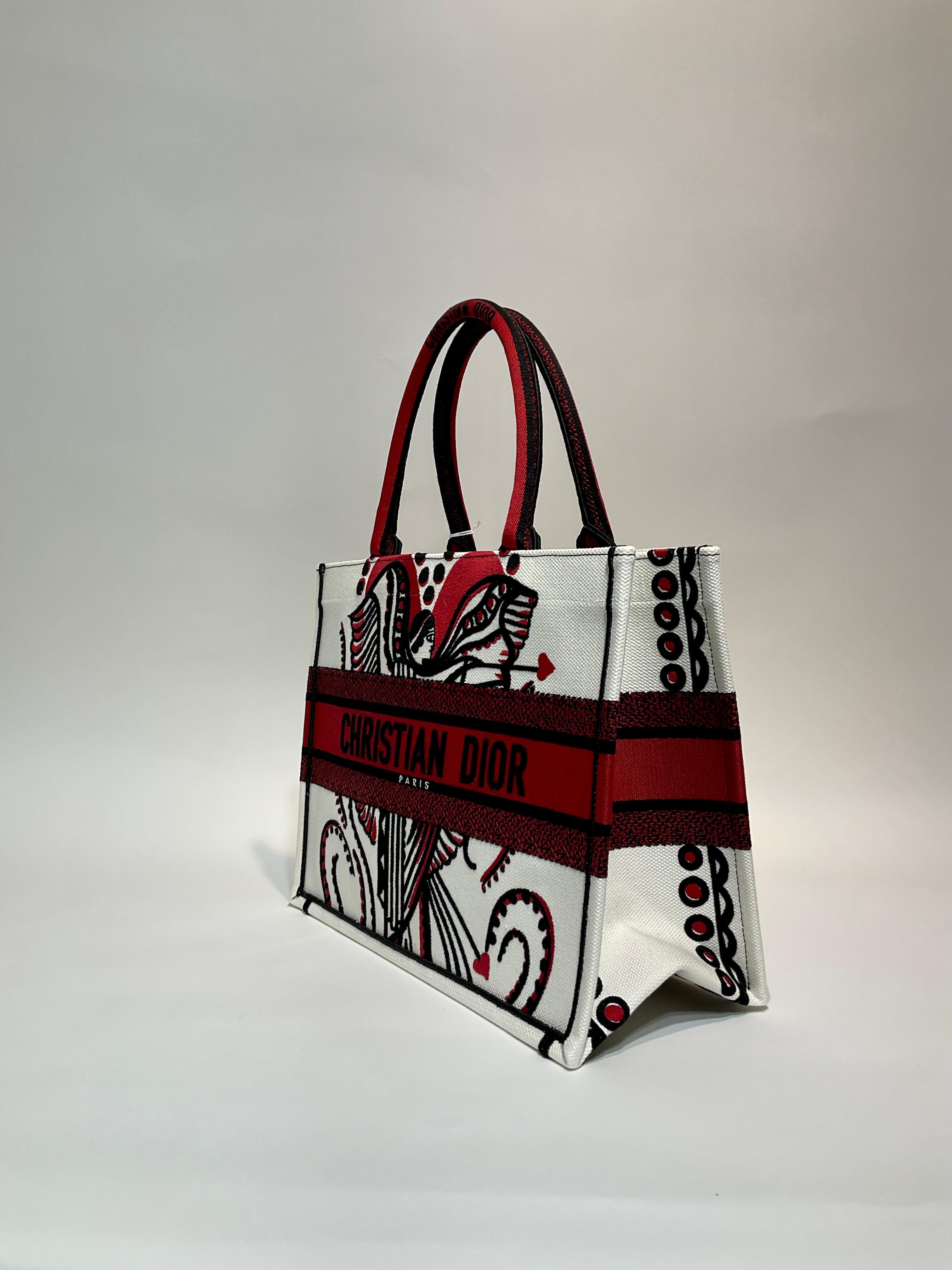 Christian Dior Embroidered Canvas Cupidon Medium Book Tote- Pristine; appears never carried.
Part of a capsule collection, this striking tote features Eros, the Greek God of Love.  Creamy winter white canvas with deep red and black accents. 