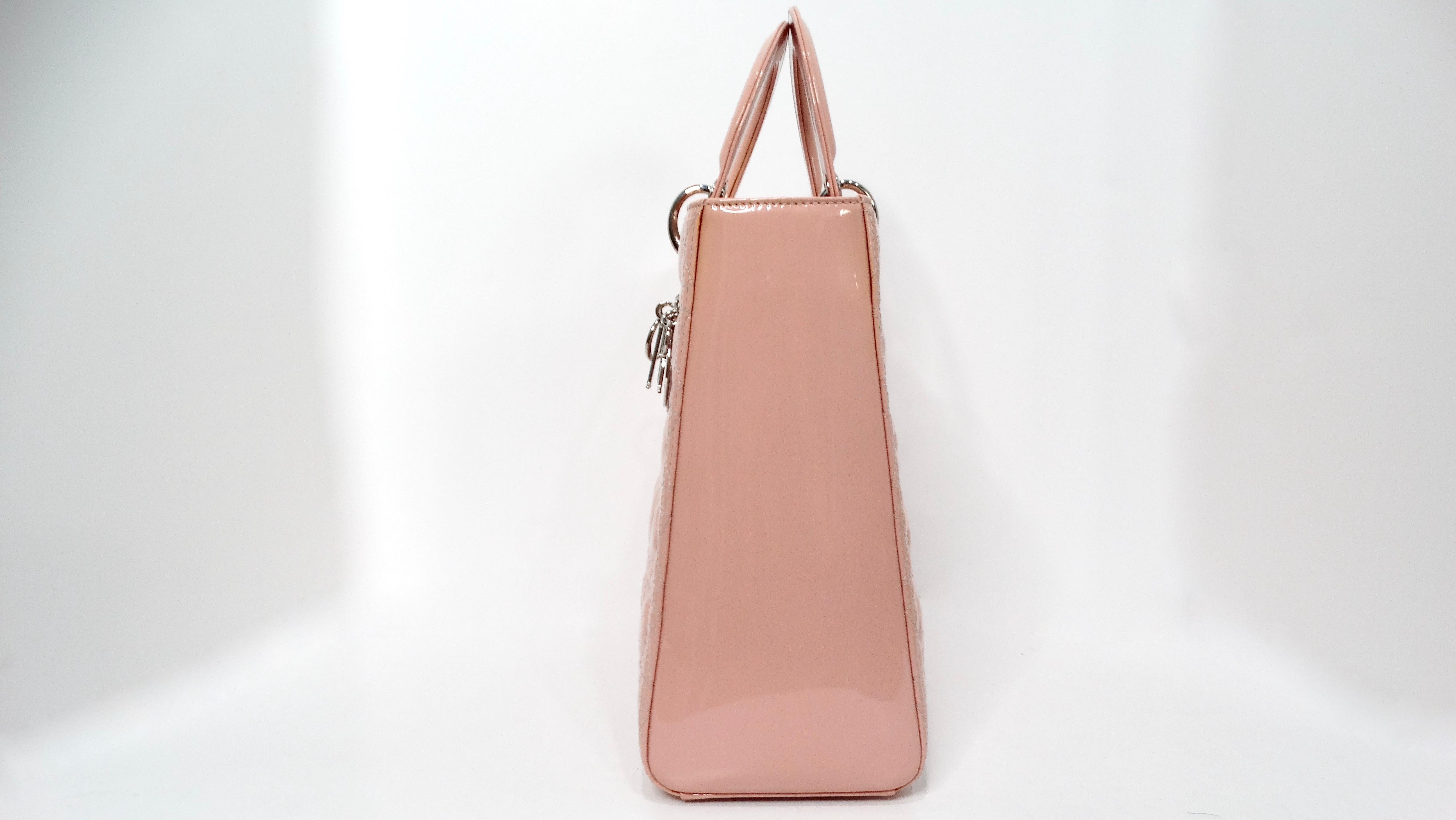 Eleganza senza tempo con la raffinata borsa Christian Dior Light Pink Patent Cannage Large. Realizzato in lussuosa pelle verniciata in una delicata tonalità rosa chiaro, questo pezzo iconico presenta le cuciture cannage tipiche di Dior, simbolo di