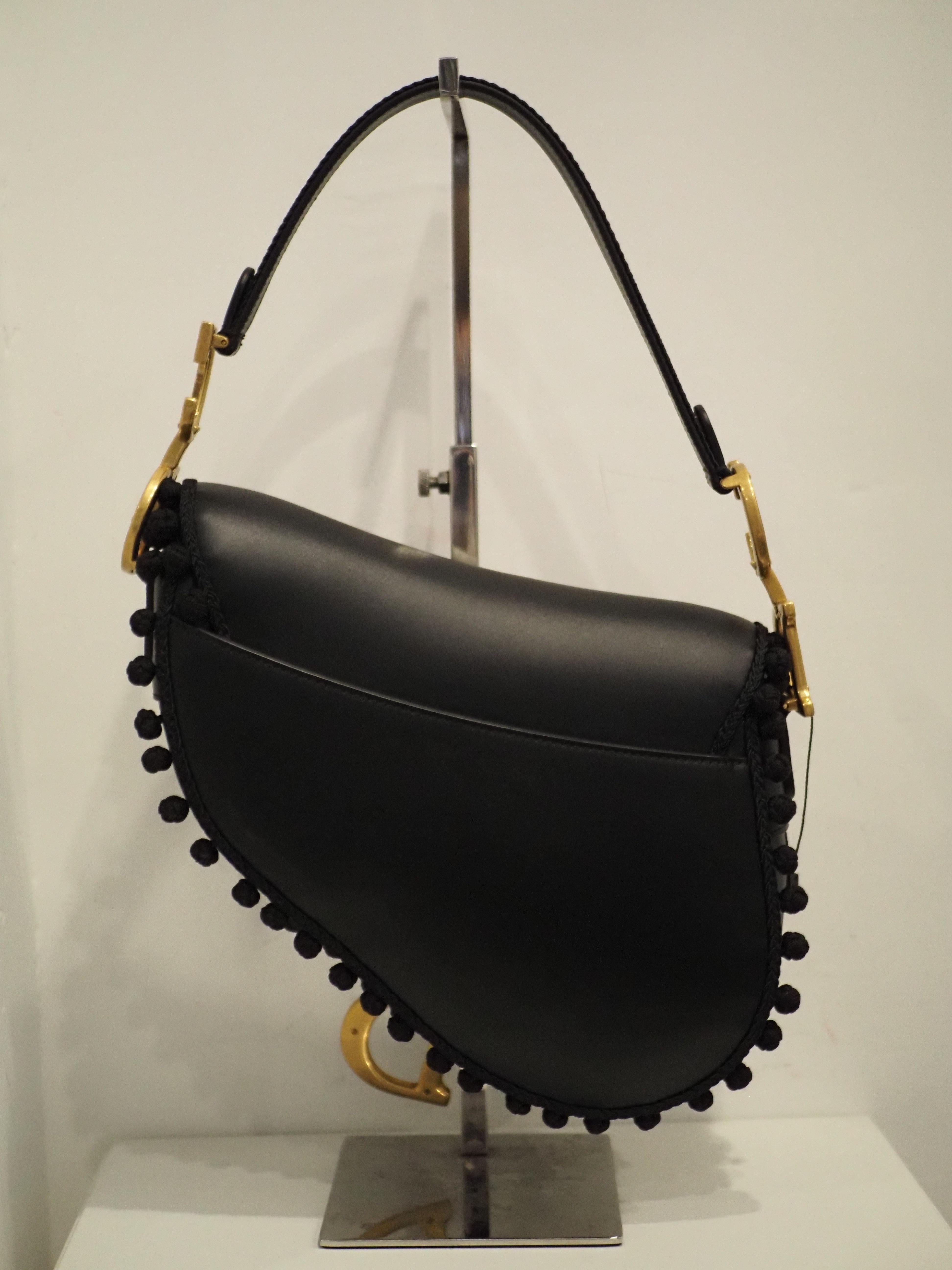 Christian Dior Limited Edition Schwarzer Leder- Pom Pom-Sattel aus Leder
schwarzes Leder mit schwarzer Stoffbommel über und über verziert, schwarzes und goldenes Logo und Hardware
perfekte Bedingungen