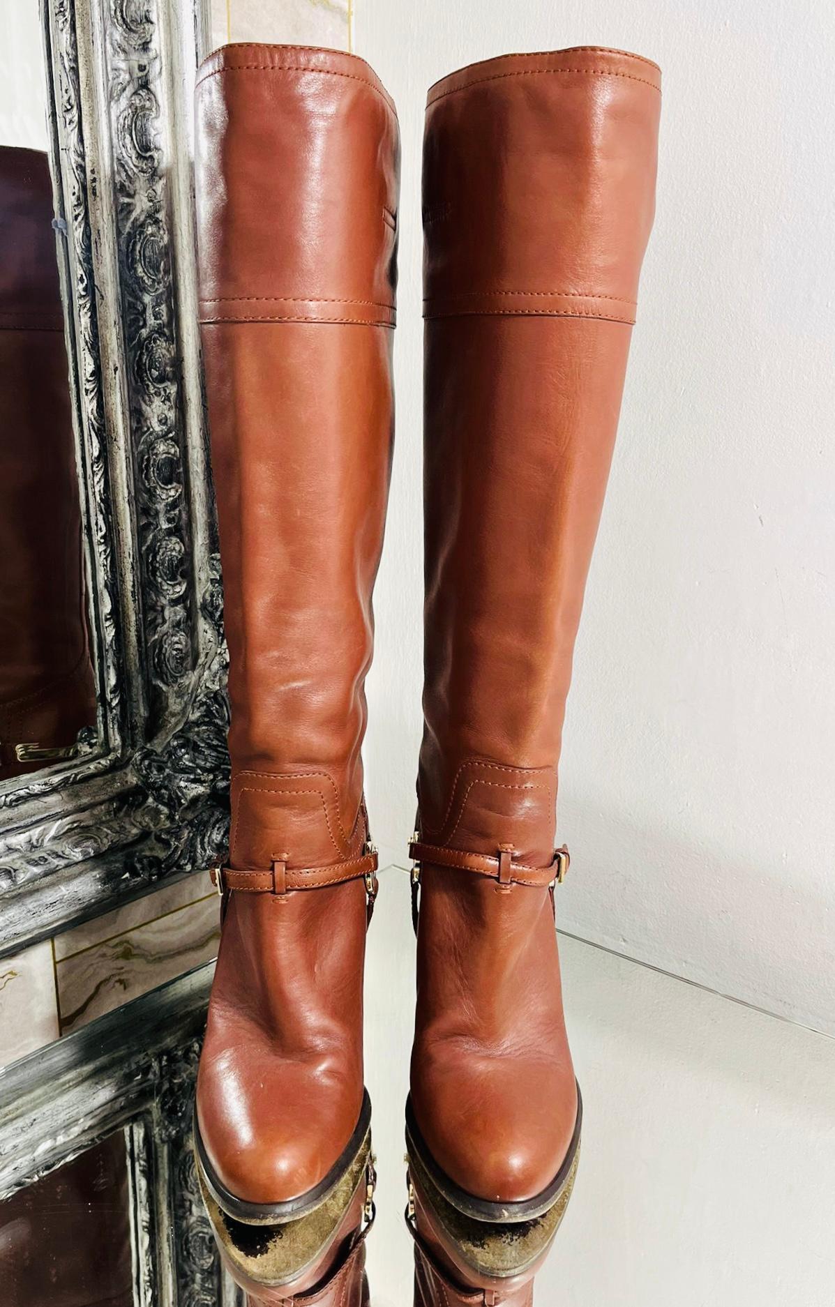 Christian Dior Logo Leather Knee Boots

Brown high boots designed with leather strap buckle detailing to the side.

Detailed with gold ring and stirrup to the heel embellished with 'CD' logo engravement.

Featuring high, block heel and pull-on