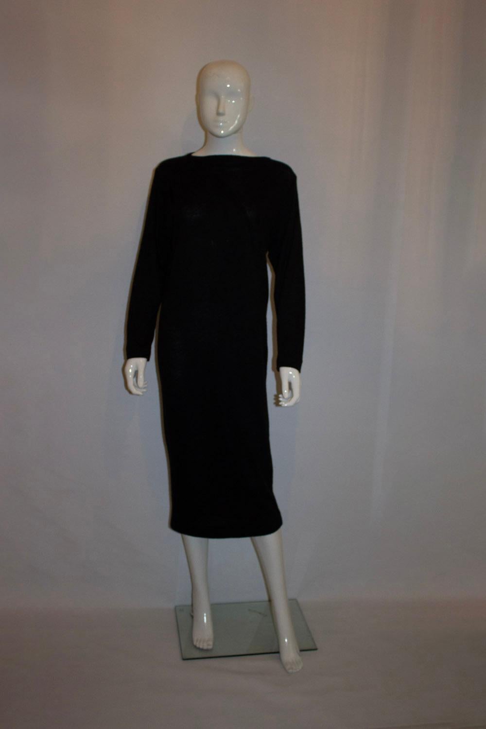  Ein schickes und leicht zu tragendes Vintage-Strickkleid von Christian Dior London. Das schwarze Pulloverkleid hat  eine Falte, eine Schulterfalte und lange Ärmel. Es ist ungefüttert und trägt das Dior-Logo.
Maße: Büste bis zu 40'', Länge 49''