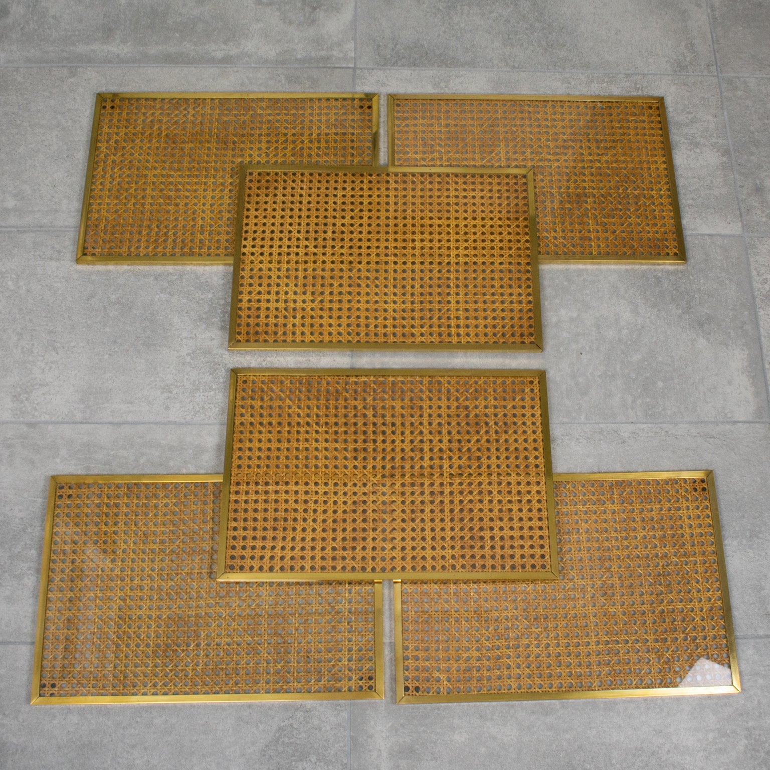 Cet élégant ensemble de six sets de table a été conçu pour la Christian Dior Interior Collection vers 1970. Les chargeurs ont une forme rectangulaire et sont encadrés de laiton poli. L'insert est en Lucite ou en acrylique cristallin avec des