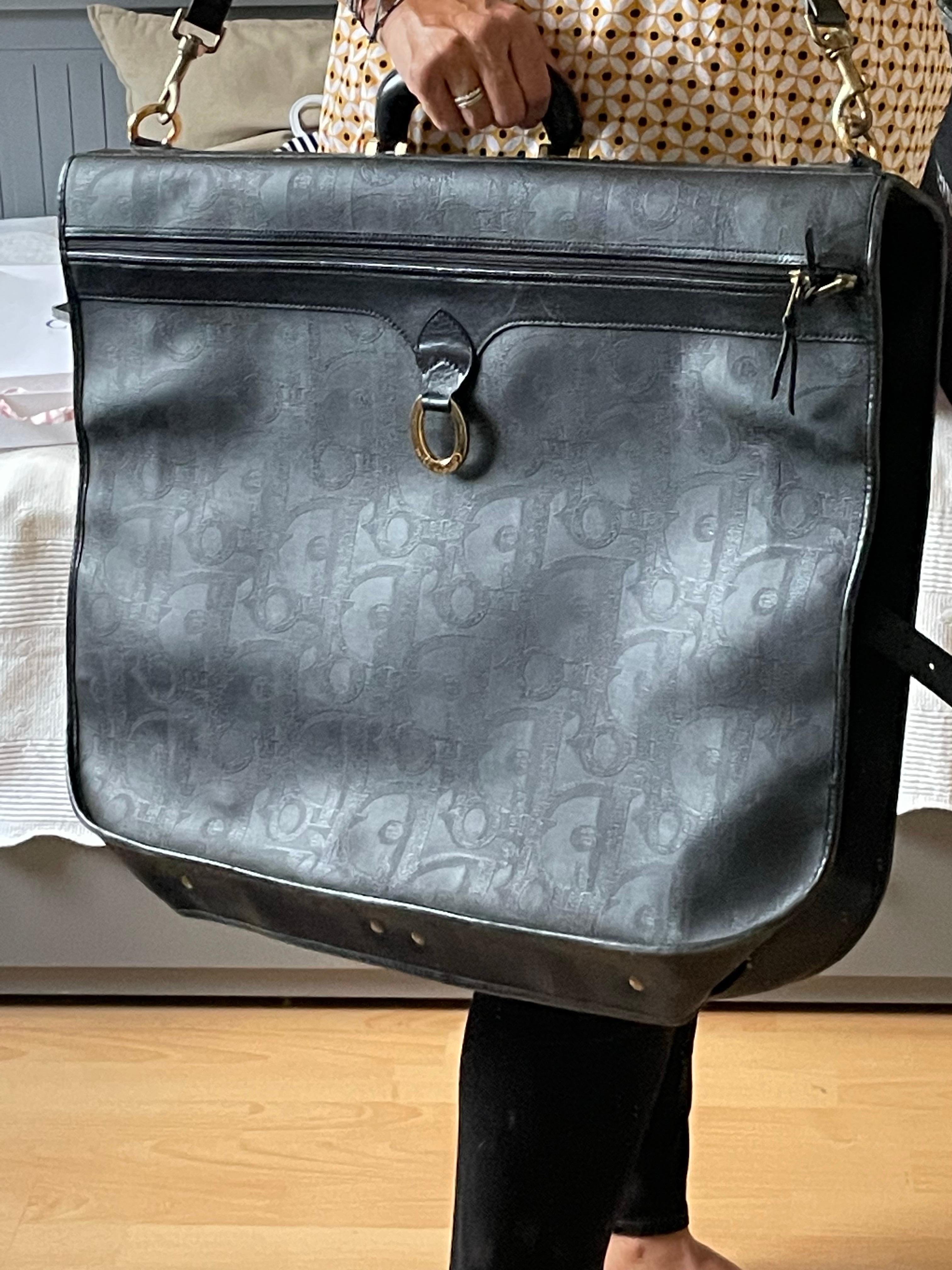 Mallette de transport de vêtements Maxi avec cintres intégrés. Monogrammes dior. Large bandoulière pour le portage à l'épaule ou poignée pour le portage à la main. La toile est en bon état. Présente de petites rayures. Hauteur totale dépliée 97 cm,