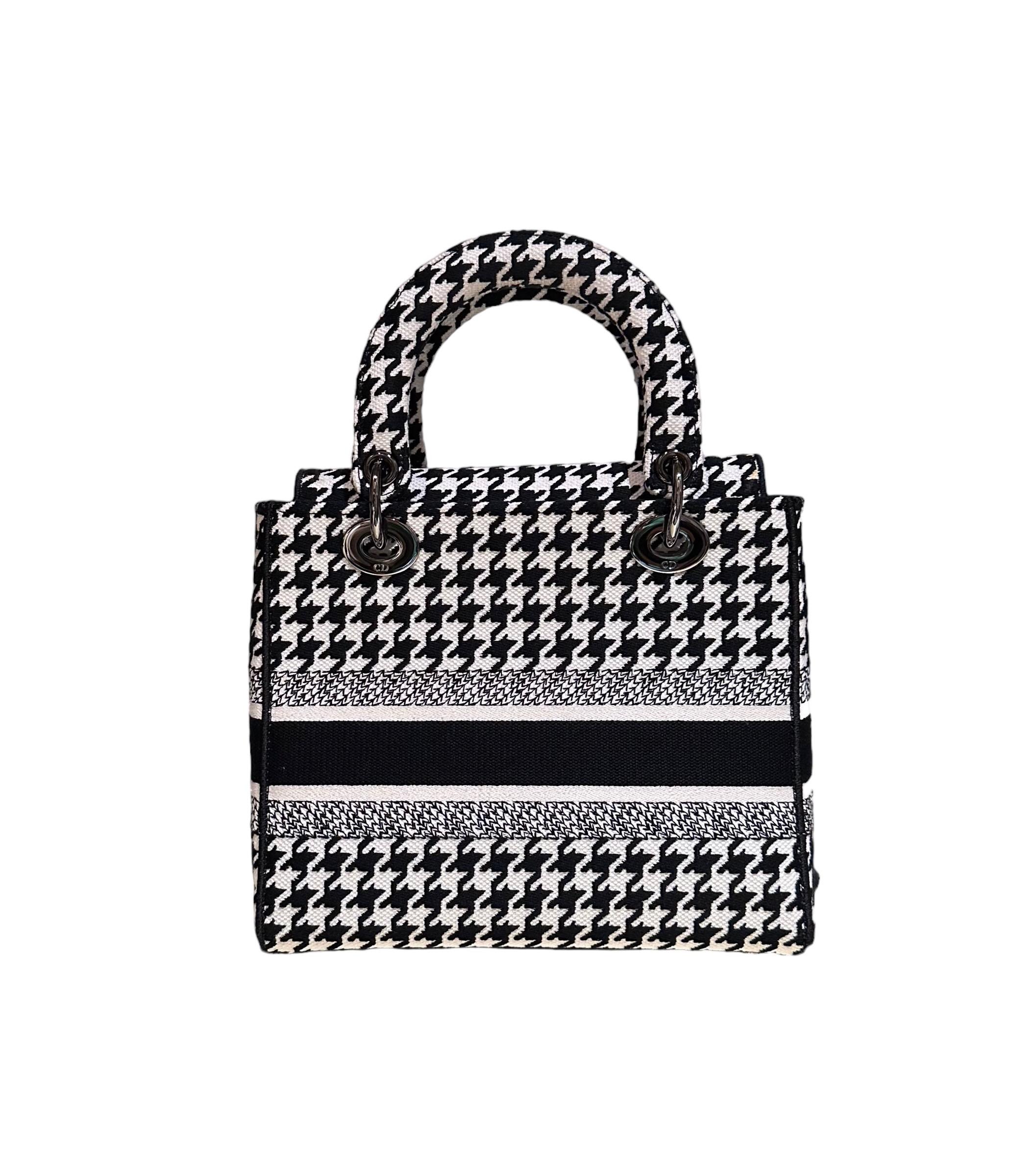 This pre-owned Lady D-Lite bag combines classic elegance with House modernity. The style is fully embroidered with the black and white Houndstooth motif, a play on the hallmark House pattern. 
The front features a Christian Dior Paris signature and