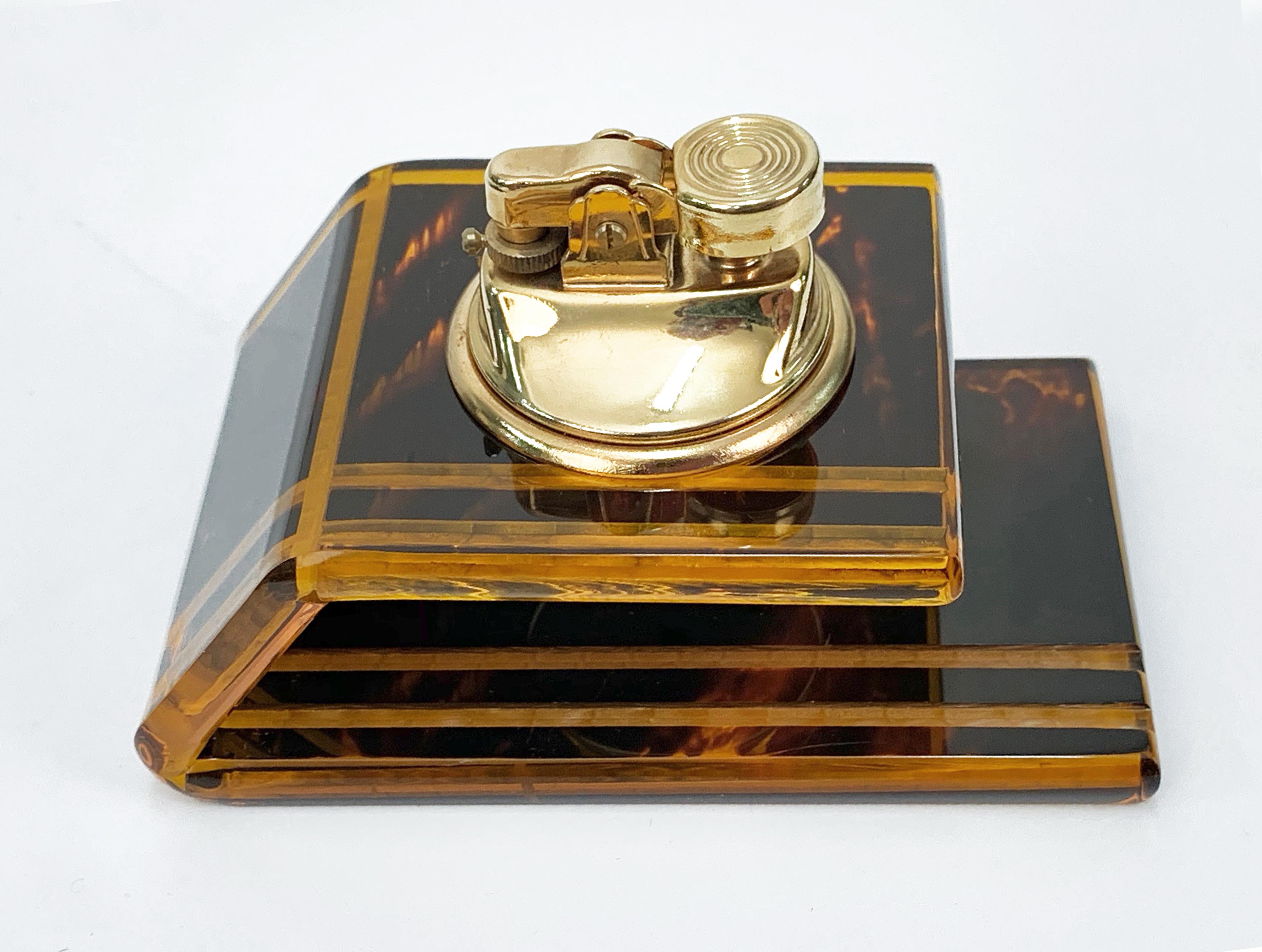 Amazing table lighter in Lucite, tortoise plexiglass and brass. Attributed to Christian Dior and produced in France during 1970s.

The item has a never-ending charm due to not having been used. It has wonderful squared lines, blunted on the