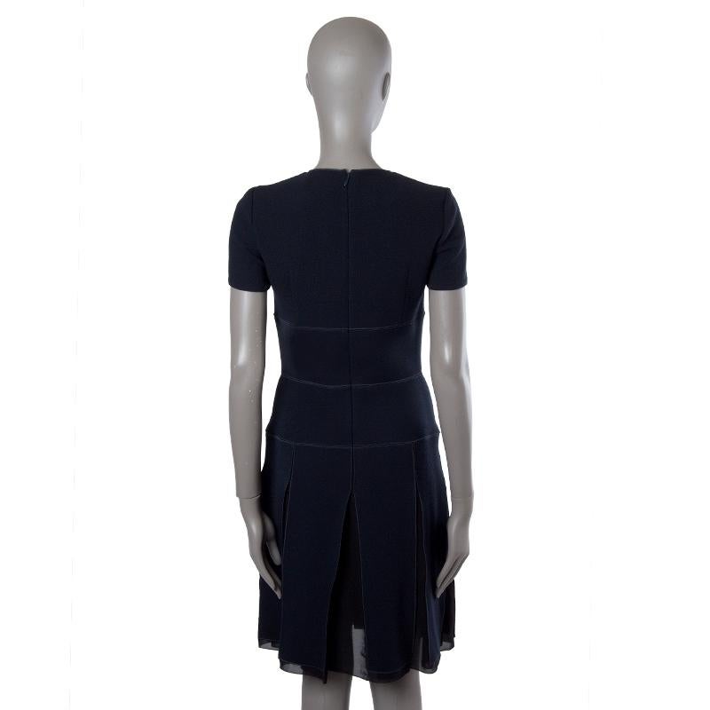 Christian Dior short-sleeve dress in midnight blue virgin wool (100%) and black silk chiffon (100%). With round neck and pleated skirt. Closes with one hook and invisible zipper on the back. Lined in black silk (100%). Has been worn and is in