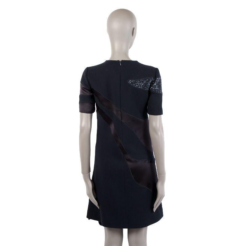 Christian Dior short sleeve paneled shift dress in midnight blue wool(100%) and silk (100%). Sequin embellished panel and flared hem. Closes with concealed zipper in the back and a hook and eye. Lined in black silk (100%). Has been worn and is in