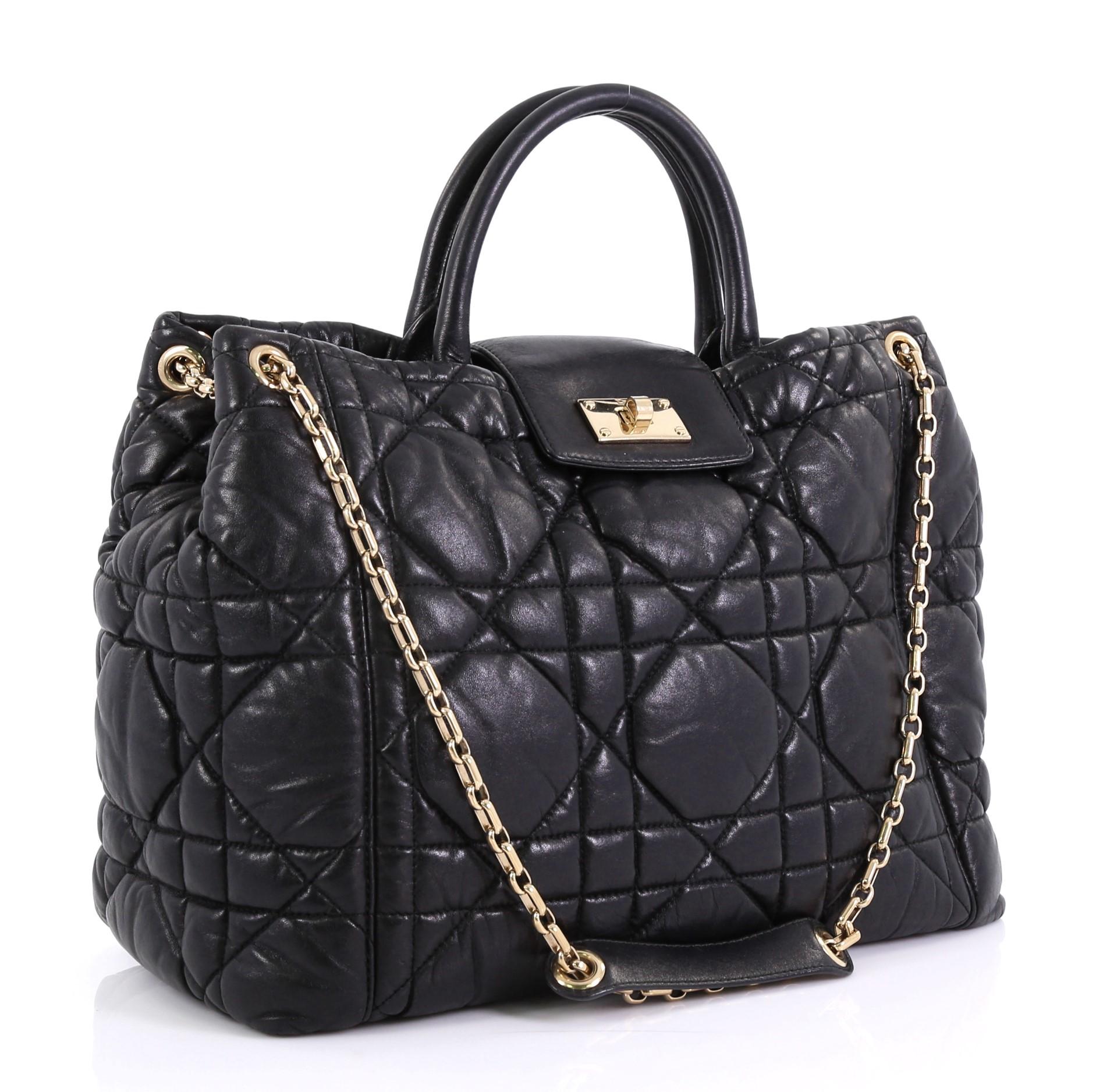 This Christian Dior Milly La Foret Shopping Tote Cannage Quilt Lambskin Large, crafted in black quilted lambskin leather, features dual-rolled leather handles, chain-link shoulder straps with leather pad, and gold-tone hardware. Its flap tab with