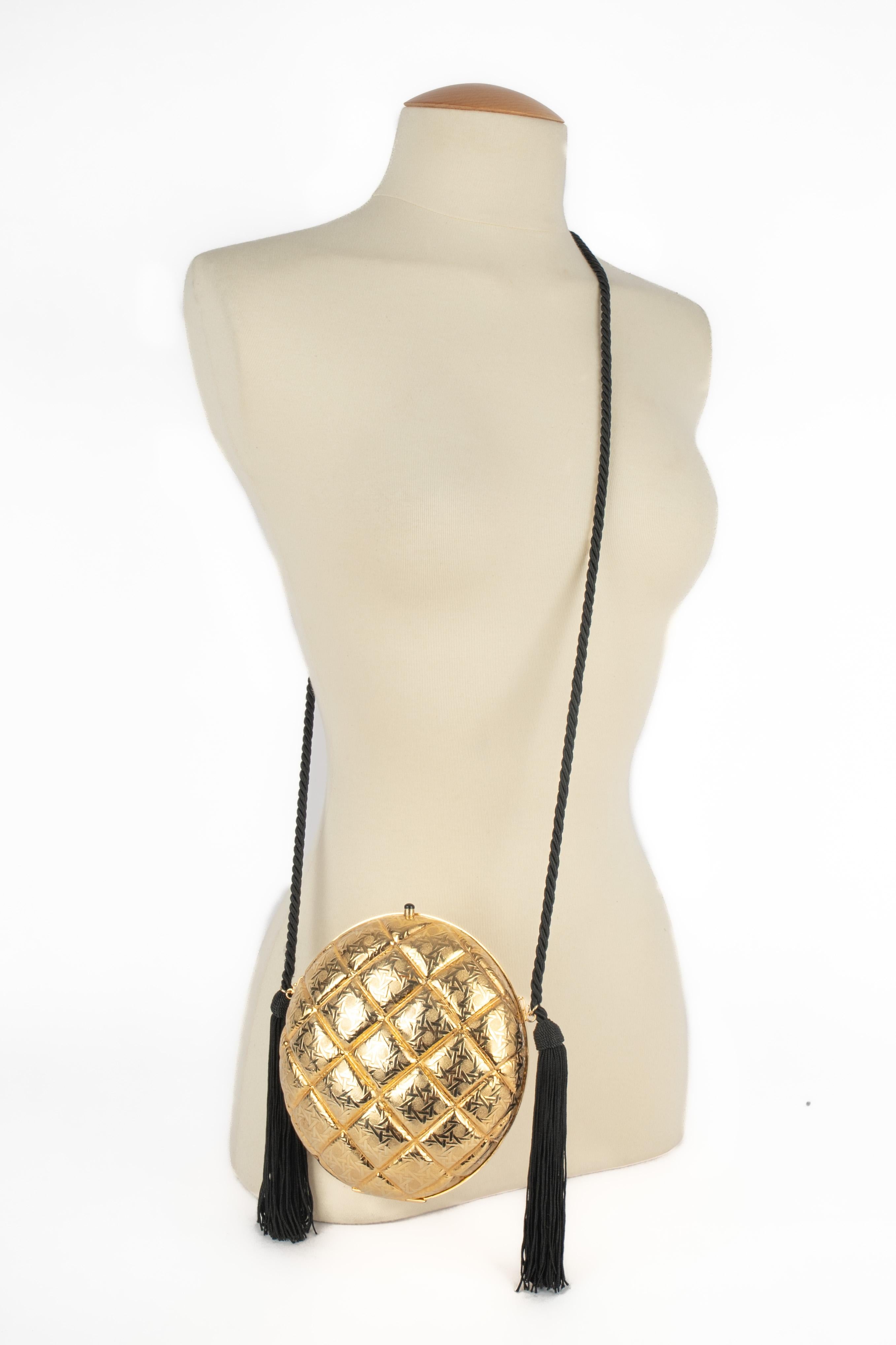 DIOR - (Fabriqué en Italie) Sac minaudière circulaire en métal doré matelassé et garnitures noires. Une Collectional des années 1990.

Condit :
Très bon état.

Dimensions :
Hauteur : 18 cm - Longueur : 18 cm - Profondeur : 2 cm - Poignée : 112