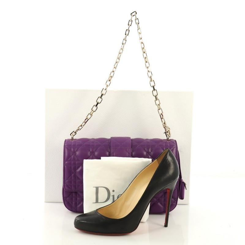 This Christian Dior Miss Dior Flap Bag Cannage Quilt Lambskin Medium, crafted in purple cannage quilted lambskin leather, features a chain link strap, front flap with push-lock closure, and gold-tone hardware. Its push-lock closure opens to a light