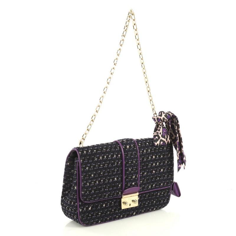 This Christian Dior Miss Dior Flap Bag Tweed Medium, crafted from black and purple tweed, features a chain link strap, frontal flap and gold-tone hardware. Its push-lock closure opens to a purple leather interior with slip pockets. 

Estimated