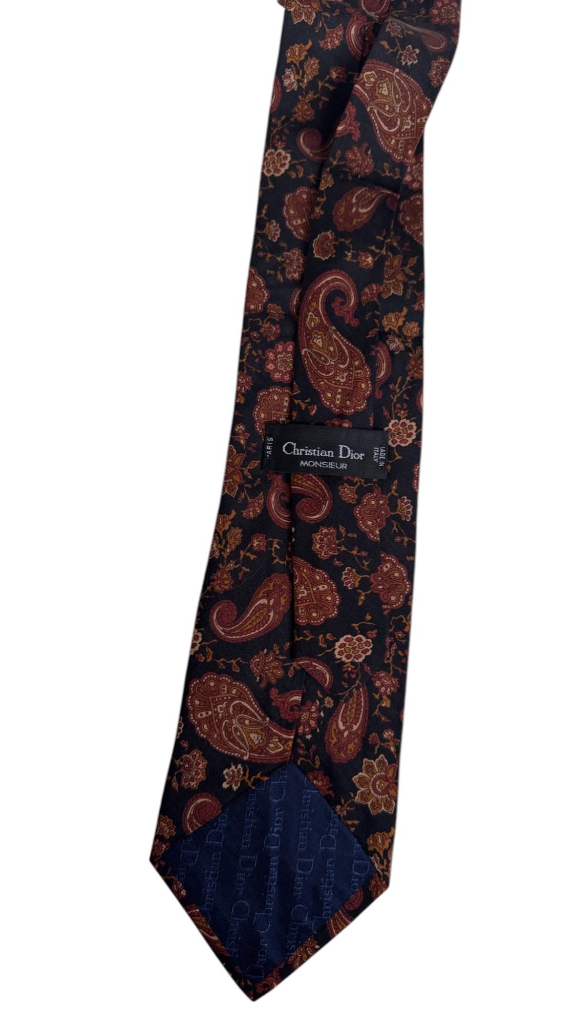Diese Vintage-Krawatte von Christian Dior Monsieur zeigt ein aufwendiges Paisleymuster in warmen Burgunder-, Gold- und Brauntönen vor einem tiefen anthrazitfarbenen Hintergrund. Sie strahlt eine zeitlose Eleganz aus, die klassische französische