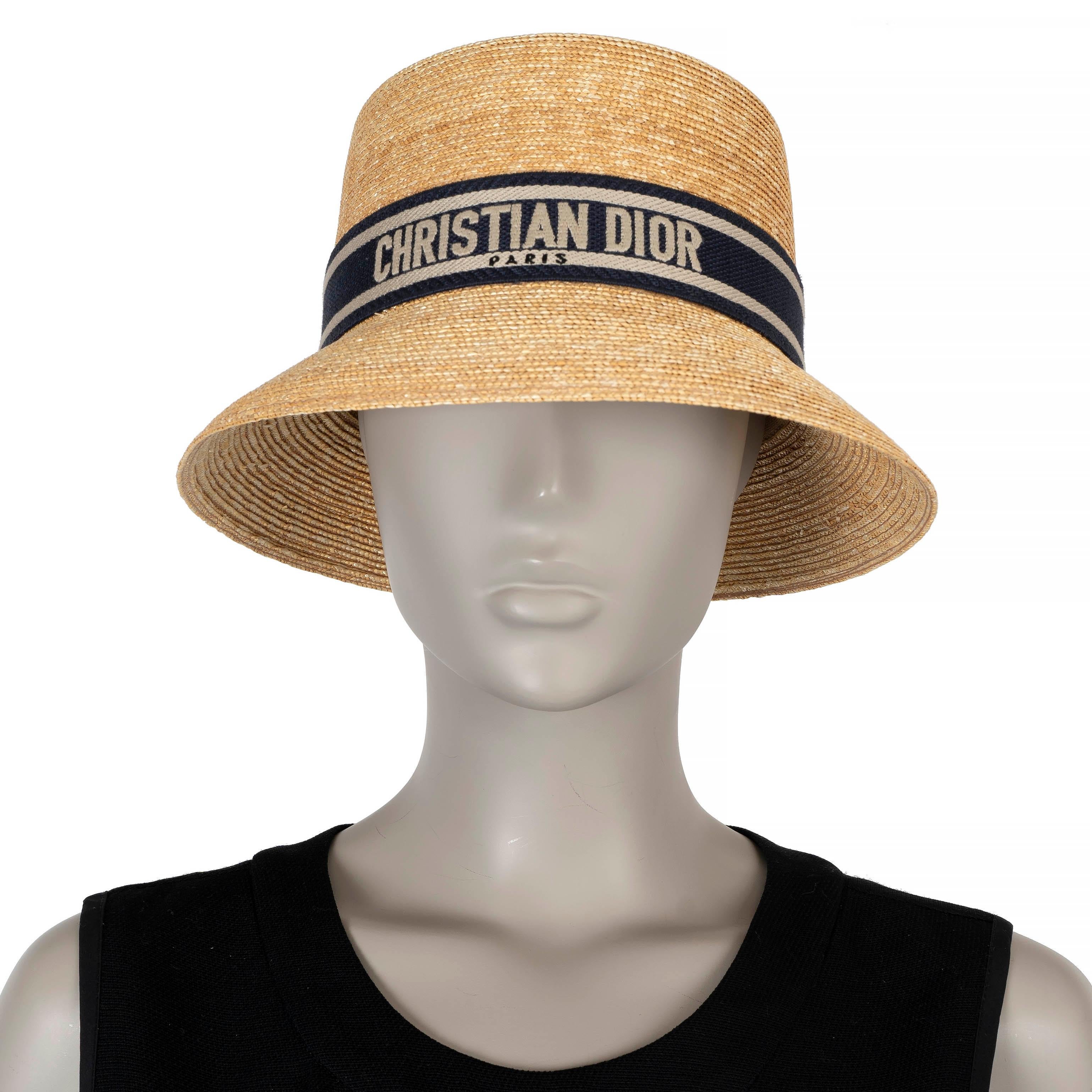 This 100% authentic Christian Dior D-Bobby Small Brim hat is crafted from natural straw, featuring a dark blue and grey logo-embroidered band. Perfect for summer or beach outings, this chic hat adds a touch of timeless elegance to any warm-weather