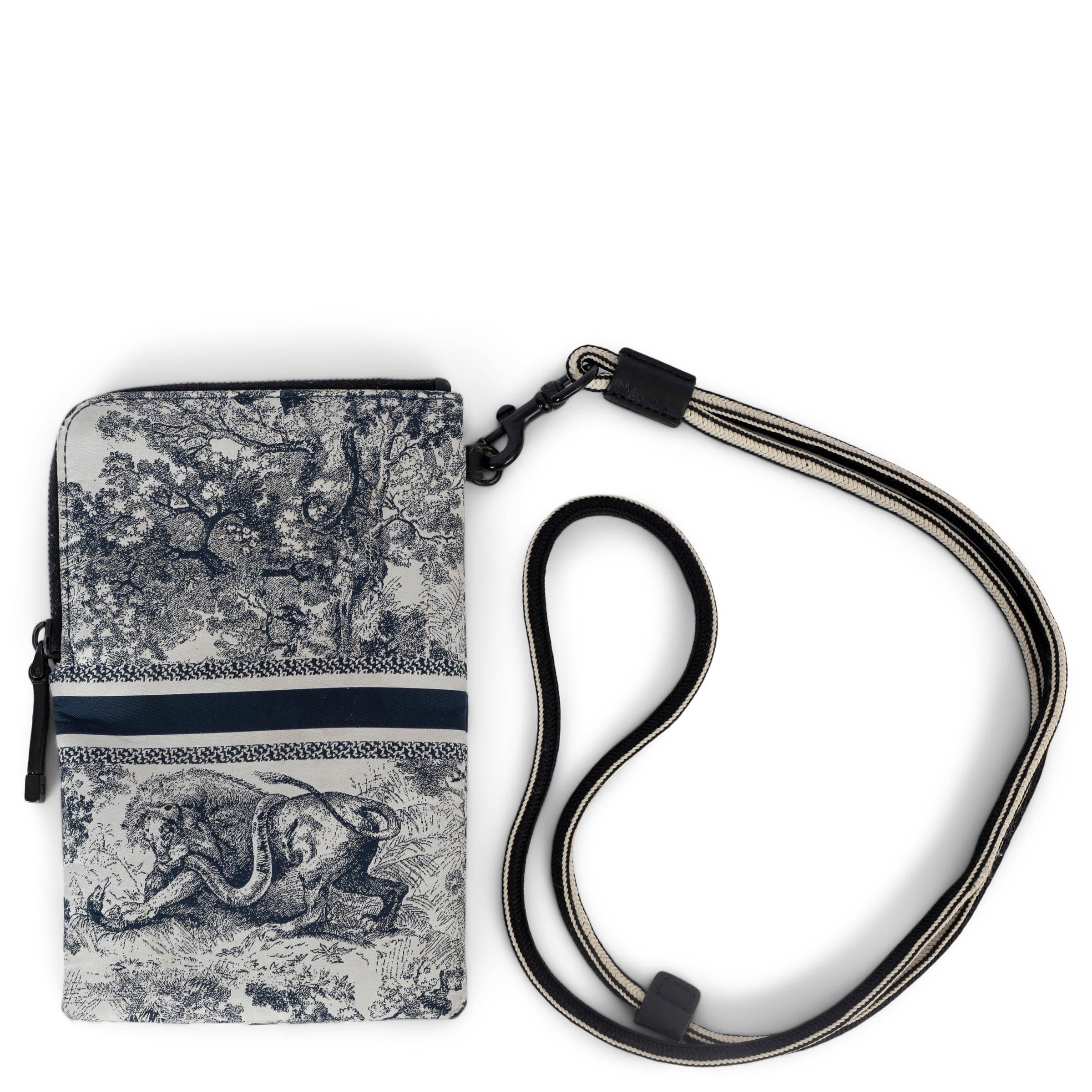 100% authentic Christian Dior DiorTravel Multifunctional pouch in navy blue and white Toile de Jouy embroidered technical canvas. Features a detachable cord strap that works crossbody. Opens with a partial zipper and is lined in nylon with two
