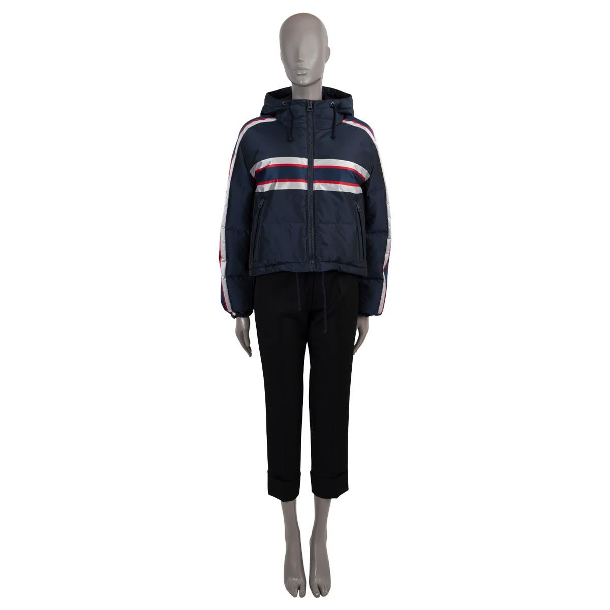 100% authentic Christian Dior hooded down puffer jacket in navy blue technical taffeta (100% polyester). Features stripe details in silver and red and Star motif on the back. The waterproof style, ideal for skiing, has a windproof membrane, interior