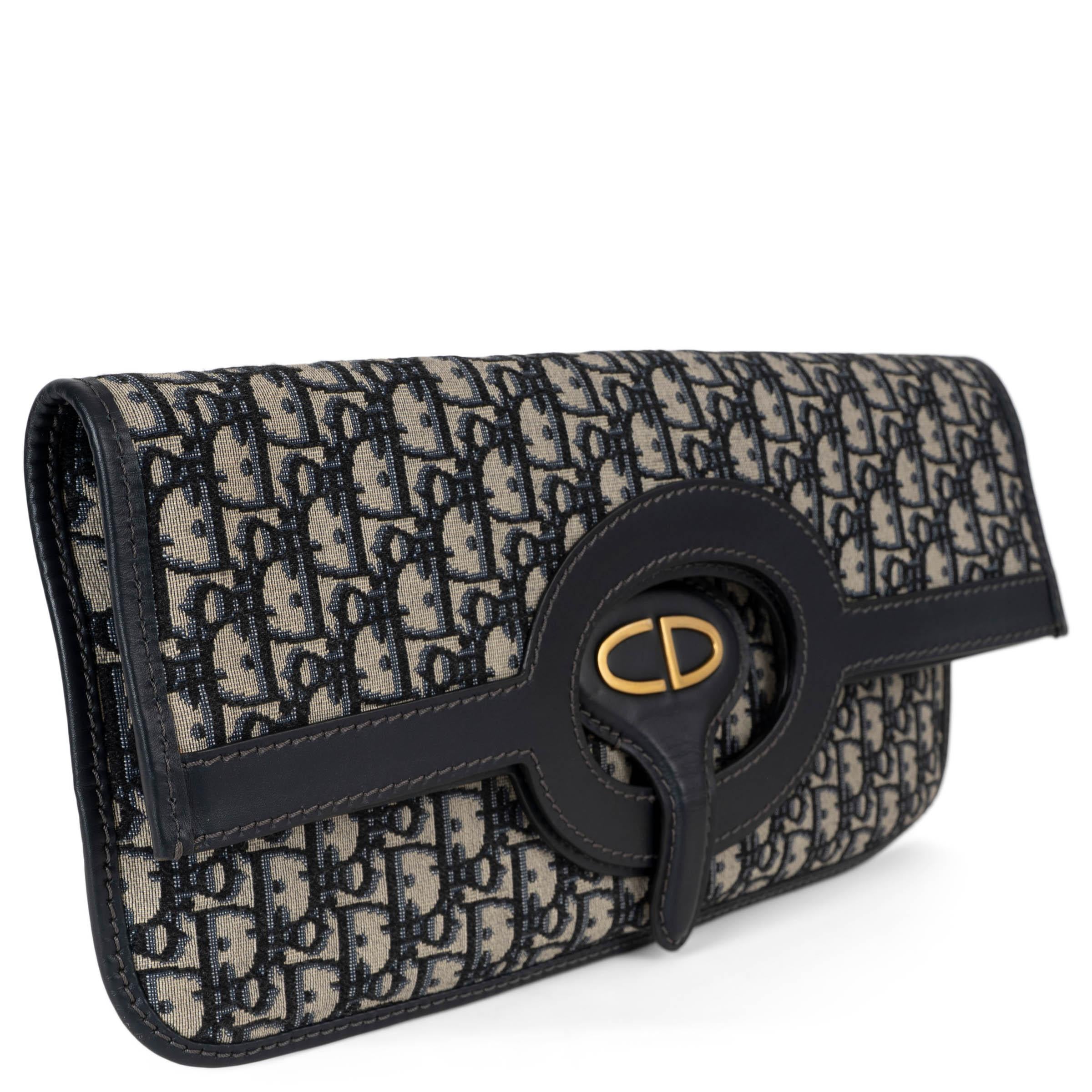 Este bolso de mano plegable 100% auténtico Christian Dior está confeccionado en lona bordada Oblique azul marino con ribetes de piel lisa. Presenta una silueta plegable con un asa redonda recortada, que permite llevarla como un bolso de mano para un