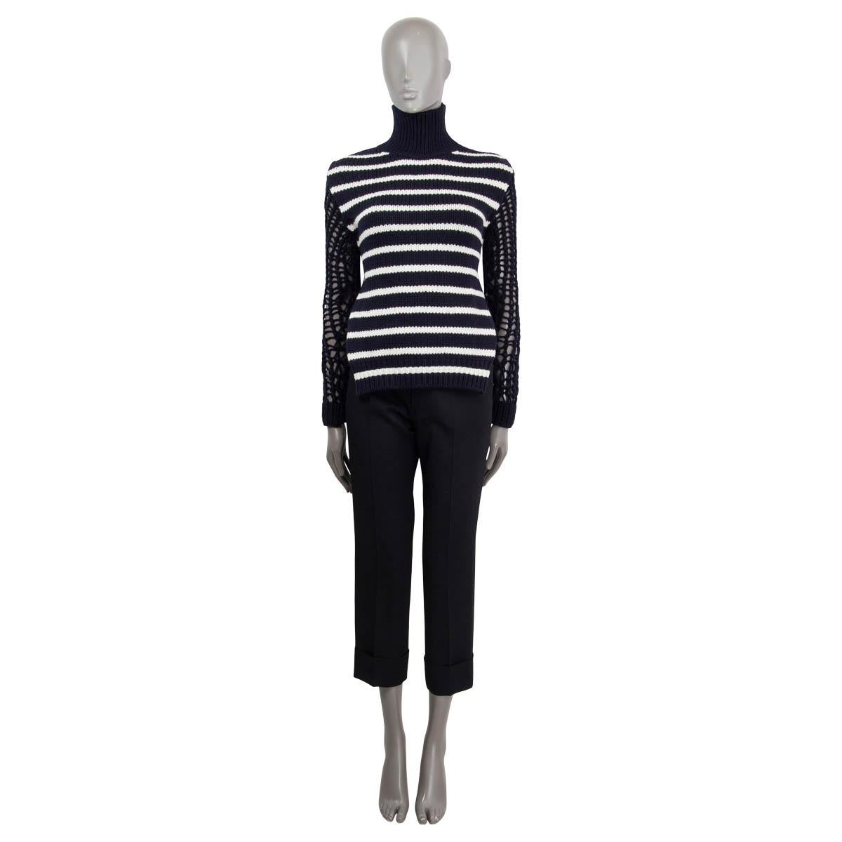 100% authentic Christian Dior open back striped turtleneck knit sweater in navy and off-white wool (70%) and polyamide (30%). Features long chunky knit sleeves and opens with a self-tie cord on the back. Unlined. Has been worn once and is in