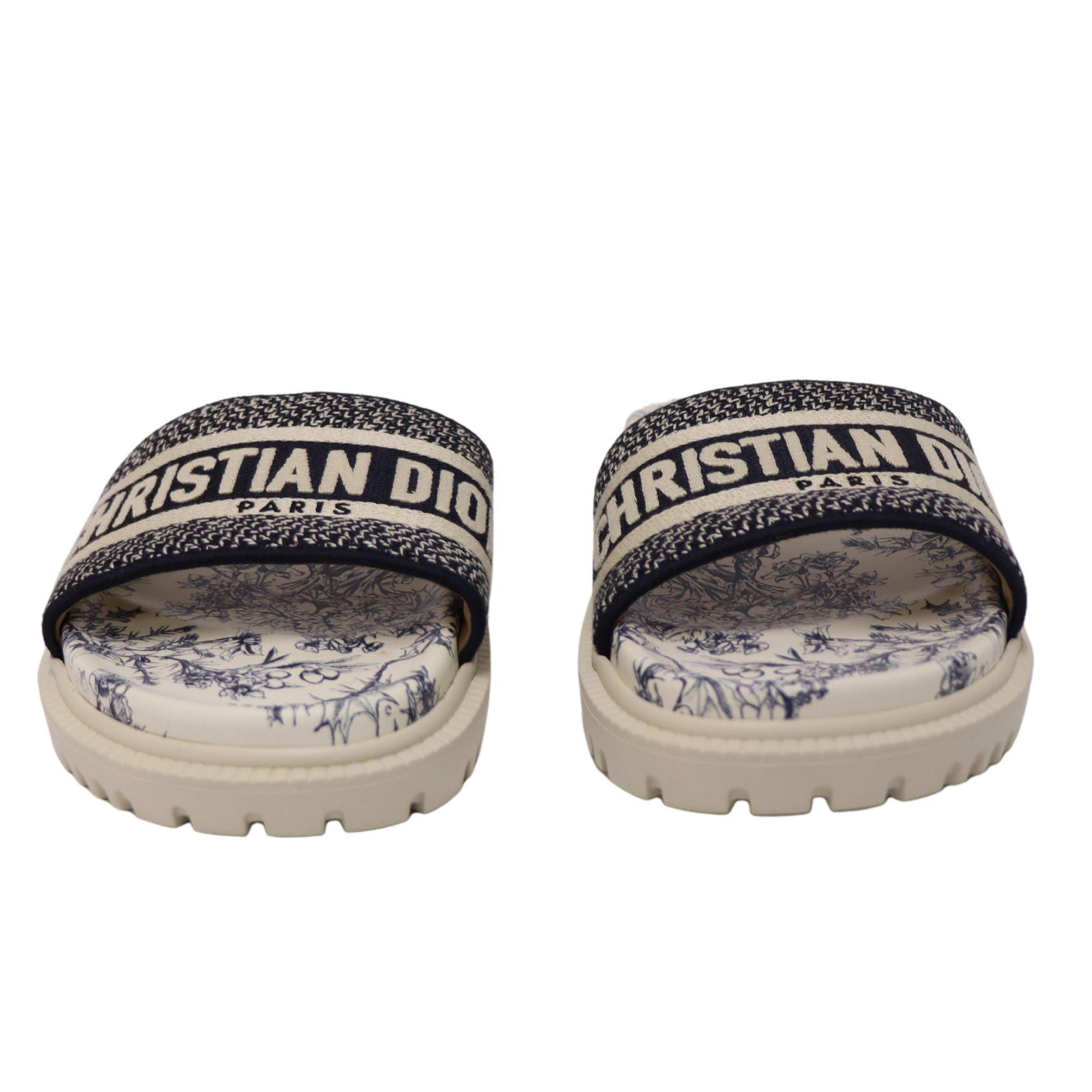 The perfect summer slipper. This New Christian Dior Slipper features navy blue and white Toile de Jouy print and logo embroidered cotton band across the front. Chunky rubber sole measures approximately 20mm/ 1 inch. 

Size: EU 38
