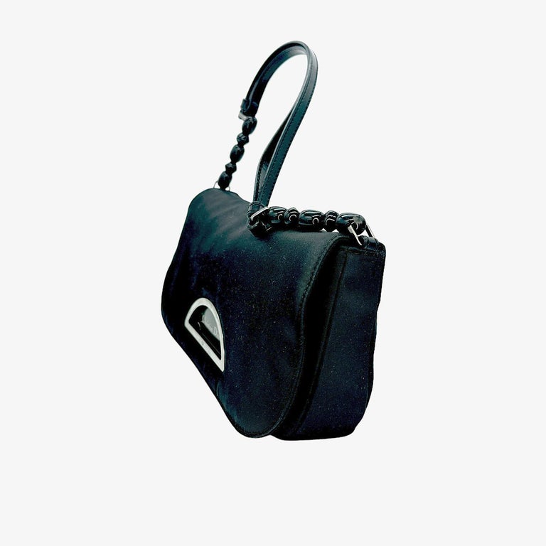 We are offering this wonderful Christian Dior Nylon Malice Baguette Black Clutch. The Malice baguette features a nylon body, a leather shoulder strap, silver-tone hardware, a front flap with a magnetic closure, and an interior zip pocket.

Every