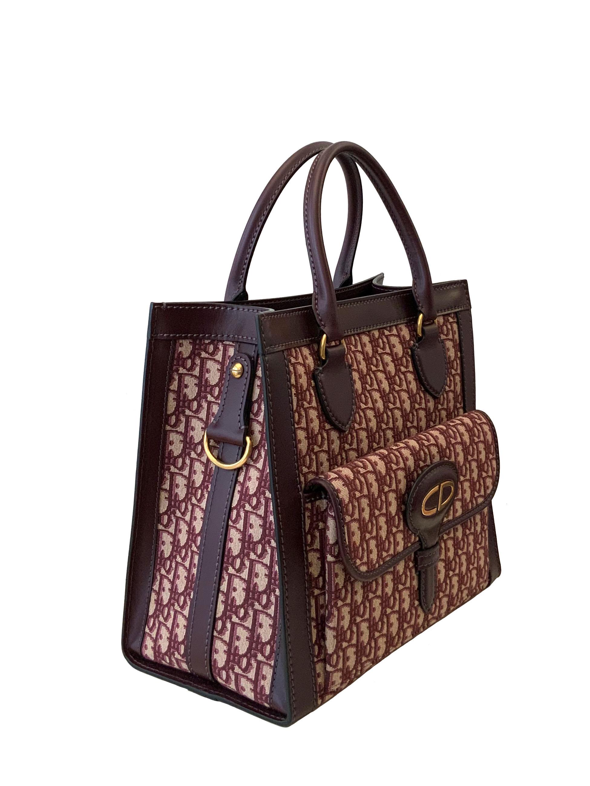 This pre-owned but new tote bag from Christian Dior is crafted in the Dior Monogram canvas in burgundy.
It features two smooth calfskin leather rolled top handles, an exterieur flap compartment and a wide detachable and ajustable shoulder strap.
The